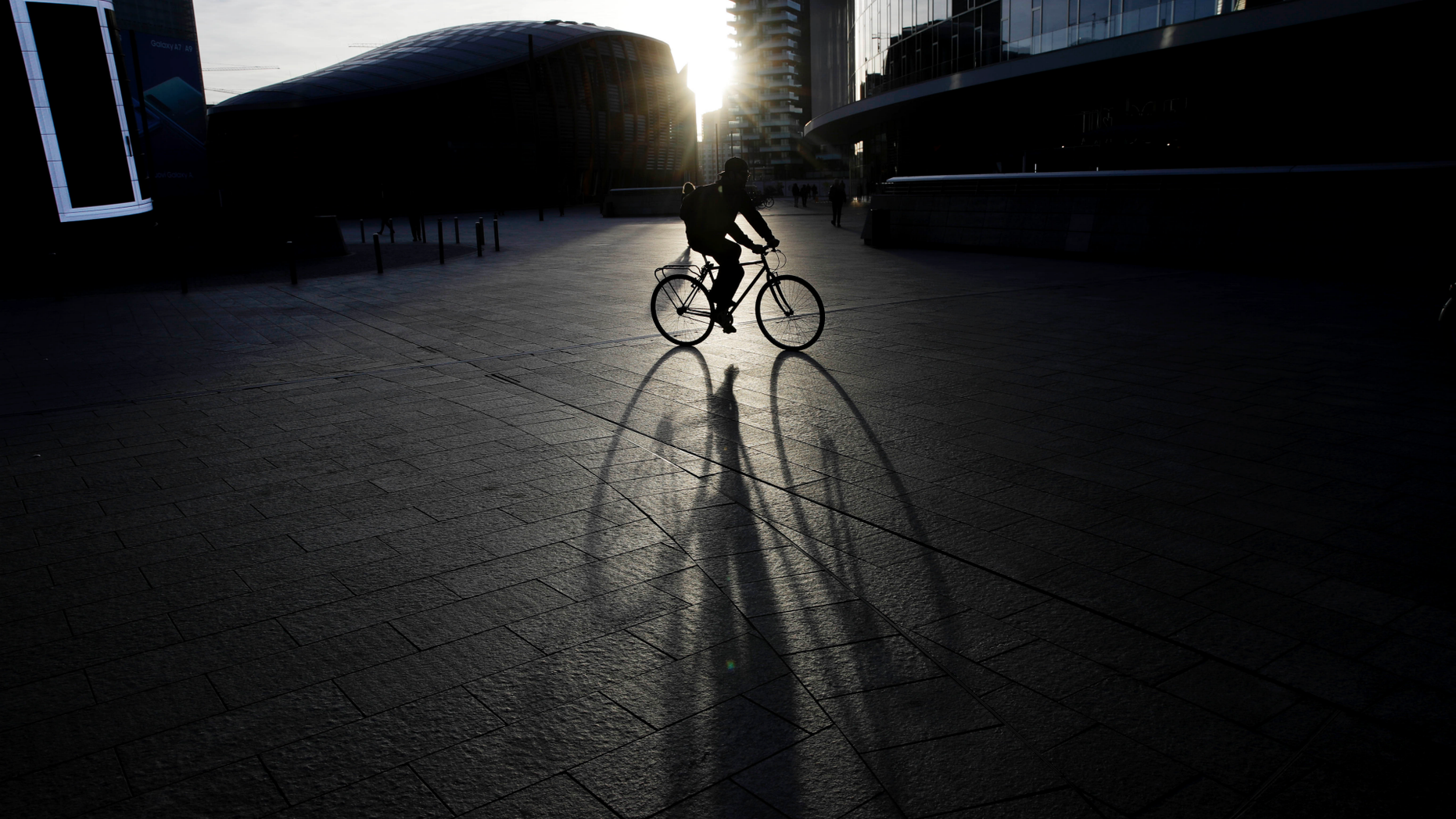 A man rides a bike in the early morning at the Porta Nuova business center in Milan, Italy, Wednesday, Oct. 24, 2018. (AP Photo/Luca Bruno)