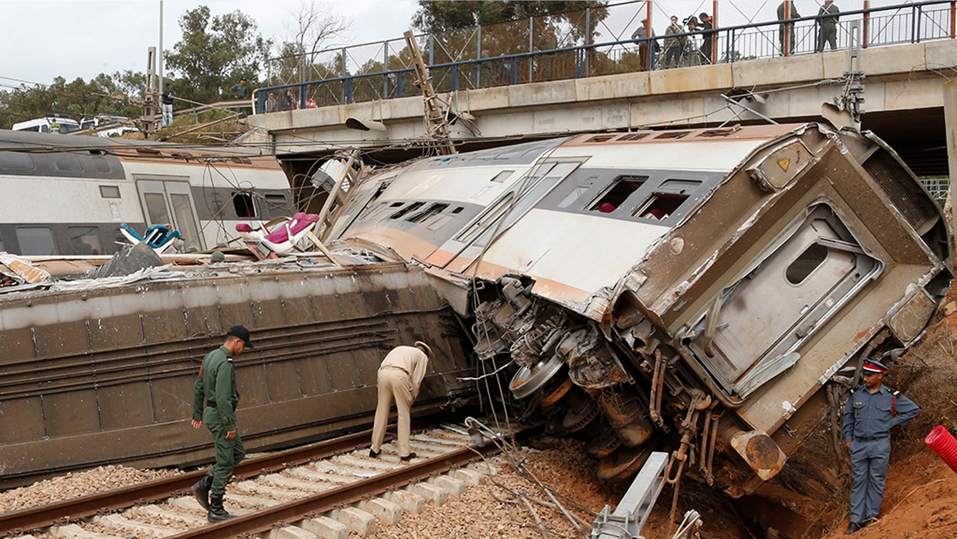 A police officer and train workers standing by a derailed train Tuesday near Sidi Bouknadel, Morocco.