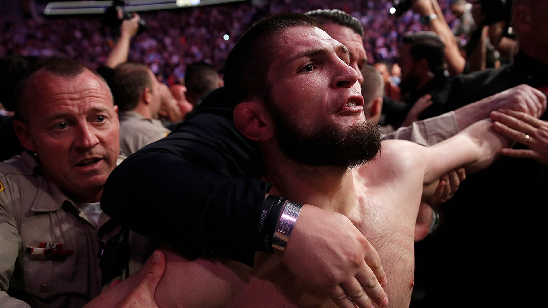 Khabib Nurmagomedov is held back outside of the cage after fighting Conor McGregor in a lightweight title mixed martial arts bout at UFC 229.