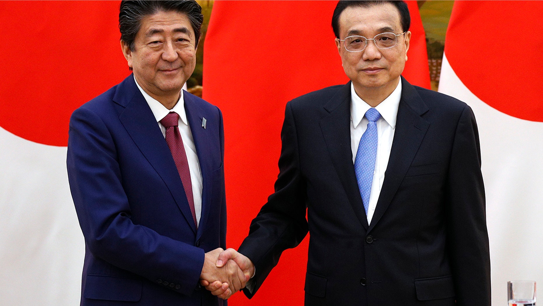 Japanese Prime Minister Shinzo Abe, left, shakes hands with Chinese Premier Li Keqiang after their joint news conference at the Great Hall of the People in Beijing, Friday, Oct. 26, 2018. (Associated Press)