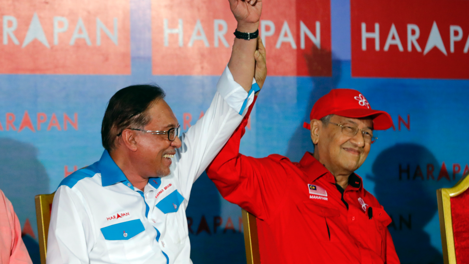 Malaysia's Prime Minister Mahathir Mohamad, right, raises hand of Malaysia's reform icon Anwar Ibrahim during a rally in Port Dickson, Monday, Oct. 8, 2018. Malaysian Prime Minister Mahathir Mohamad attended a by-election campaign to support his designated successor Anwar Ibrahim. It was the first time in 20 years that the two leaders had shared a campaign stage, after setting aside their long-standing political feud to form an alliance that won in May national elections. Anwar will run in a by-election in the southern coastal town of Port Dickson on Sunday in a bid to return to parliament and prepare for his eventual take-over from Mahathir. (AP Photo/Vincent Thian)