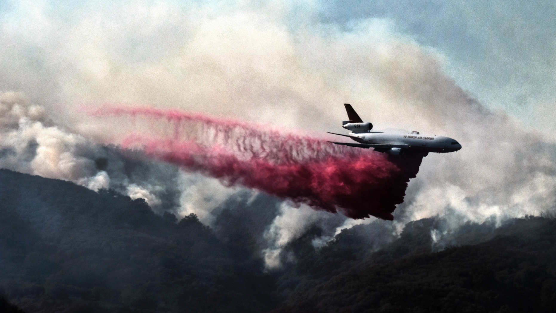 A firefighting DC-10 makes a fire retardant drop over a wildfire in the mountains near Malibu Canyon Road in Malibu, Calif. on Sunday, Nov. 11, 2018. Strong Santa Ana winds have returned to Southern California, fanning a huge wildfire that has scorched a string of communities west of Los Angeles. A one-day lull in the dry, northeasterly winds ended Sunday morning and authorities warn that the gusts will continue through Tuesday. (AP Photo/Richard Vogel)