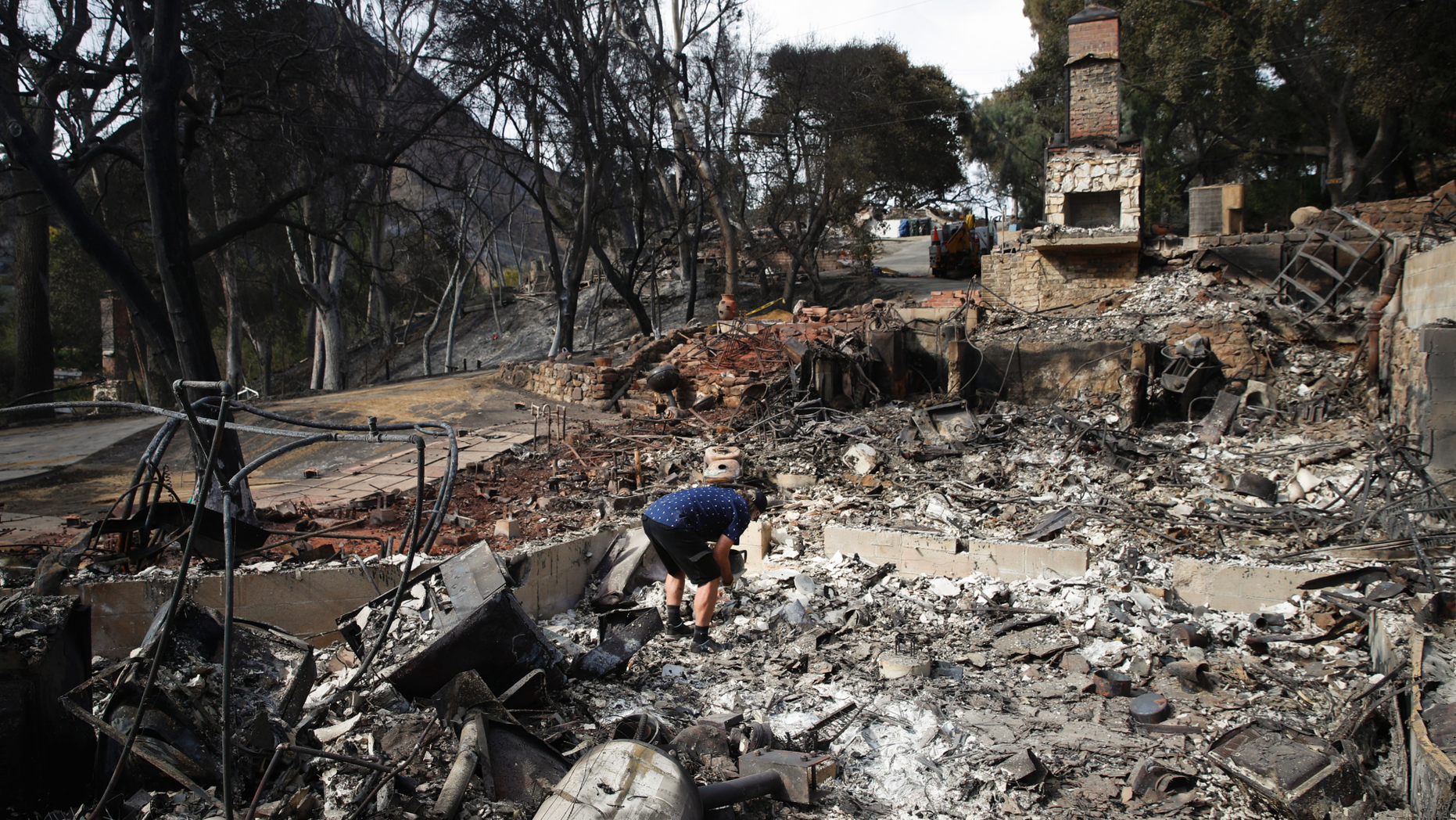 Roger Kelton searches through the remains of his mother-in-law's home leveled by the Woolsey Fire, Tuesday, Nov. 13, 2018, in the southern California city of Agoura Hills. (AP Photo/Jae C. Hong)