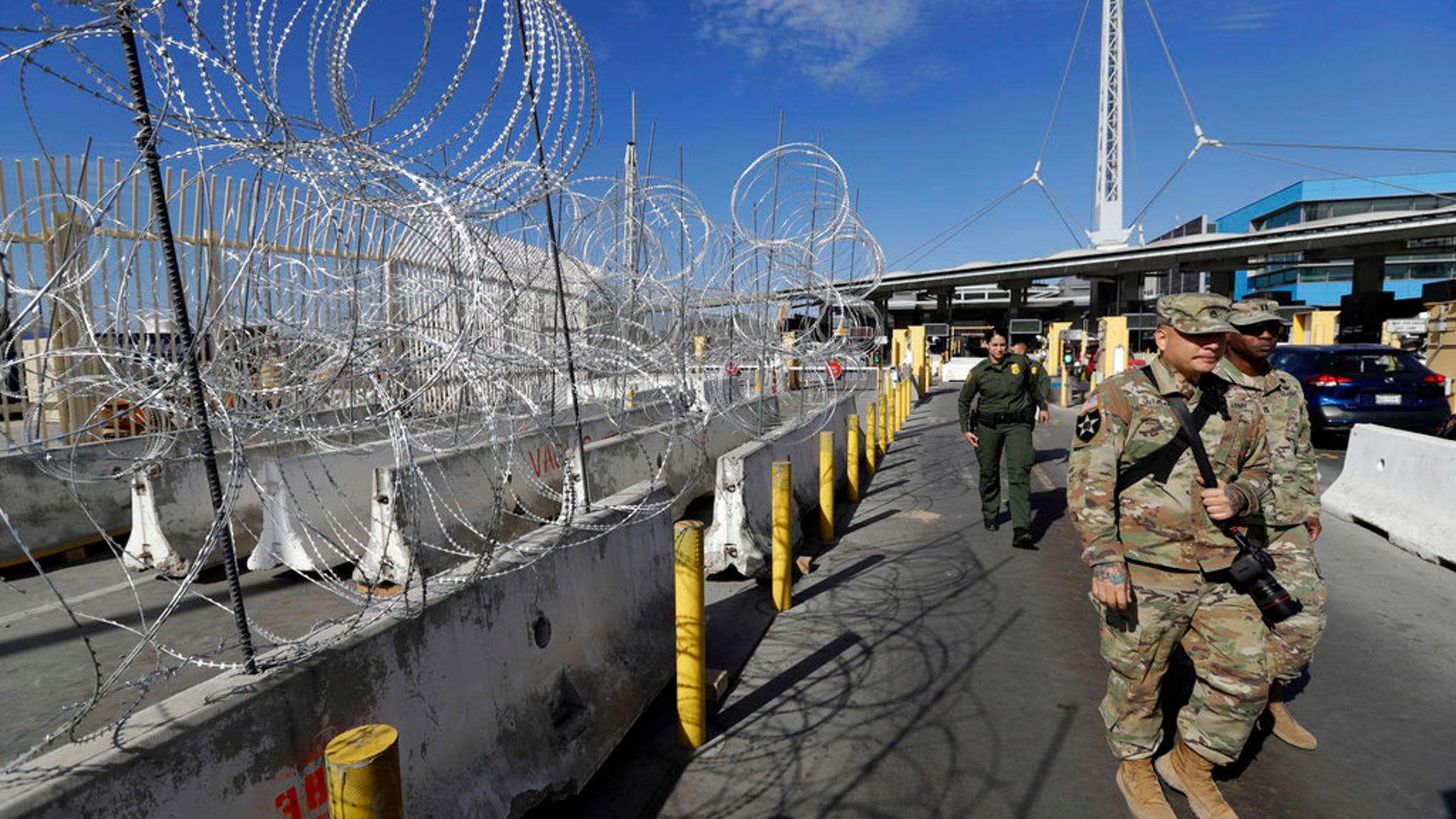 U.S. Border Patrol agents and members of the military pass concertina wire during a tour of the San Ysidro port of entry in San Diego.