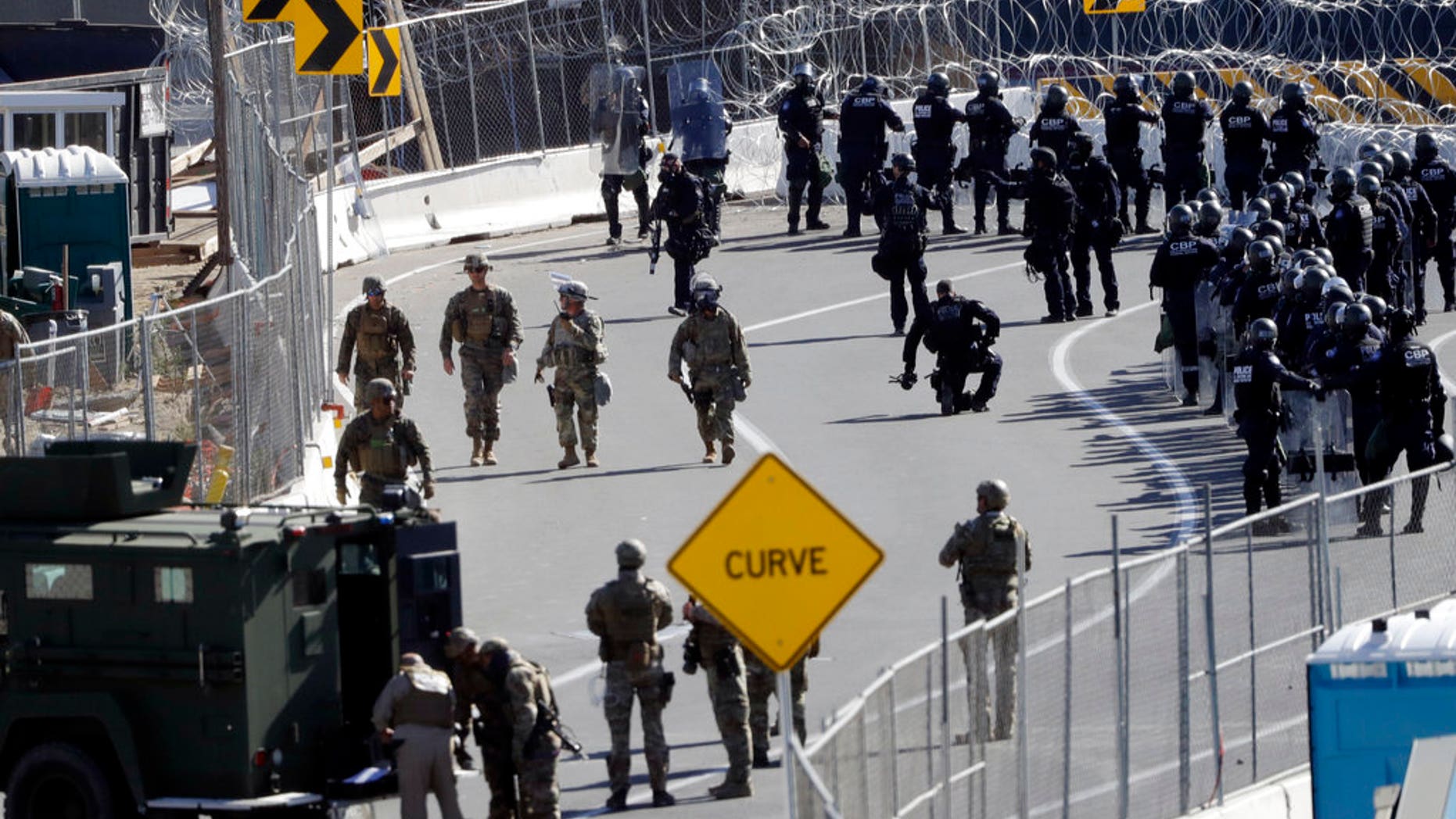 FILE: Military personnel and Customs and Border Protection officers gather along the southbound lanes of the San Ysidro port of entry in San Diego.