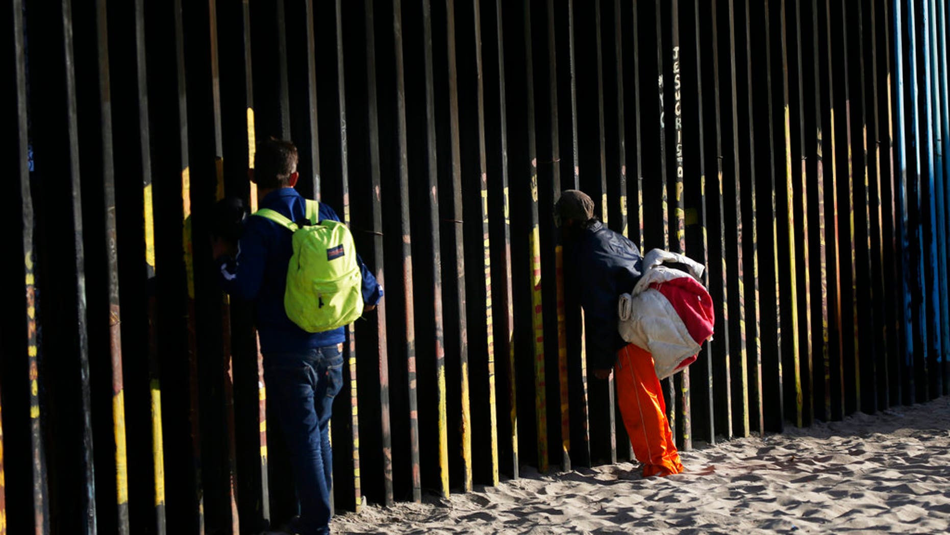 Central American migrants look through the border structure. (AP Photo/Marco Ugarte)