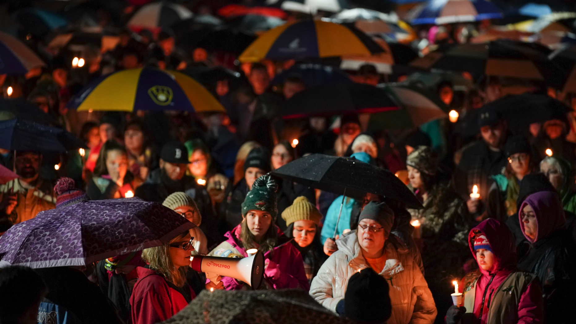 Sherri Jasper, a Girl Scout board member and counselor at Halmstad Elementary School, leads the program for a candlelight vigil at the school in Chippewa Falls, Wis., Sunday evening, Nov. 4, 2018. The western Wisconsin community on Sunday was grieving the deaths of three Girl Scouts and a parent who were collecting trash Saturday along a rural highway when police say a pickup truck veered off the road and hit them before speeding away. The 21-year-old driver, Colten Treu of Chippewa Falls, sped off but later surrendered. He will be charged with four counts of homicide, Lake Hallie police Sgt. Daniel Sokup said. (Jeff Wheeler/Star Tribune via AP)