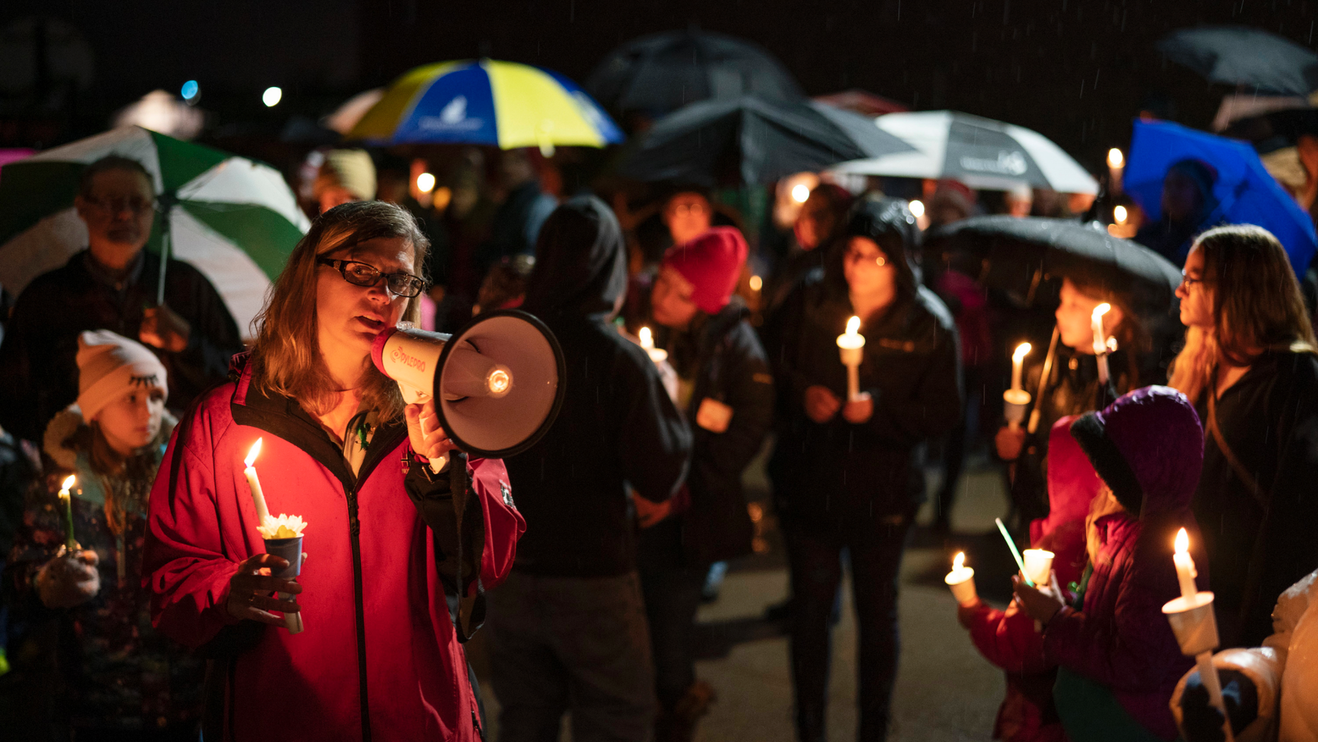 Sherri Jasper, a Girl Scout board member and counselor at Halmstad Elementary School, leads the program for a candlelight vigil at the school in Chippewa Falls, Wis., Sunday evening, Nov. 4, 2018. The western Wisconsin community on Sunday was grieving the deaths of three Girl Scouts and a parent who were collecting trash Saturday along a rural highway when police say a pickup truck veered off the road and hit them before speeding away. The 21-year-old driver, Colten Treu of Chippewa Falls, sped off but later surrendered. He will be charged with four counts of homicide, Lake Hallie police Sgt. Daniel Sokup said. (Jeff Wheeler/Star Tribune via AP)