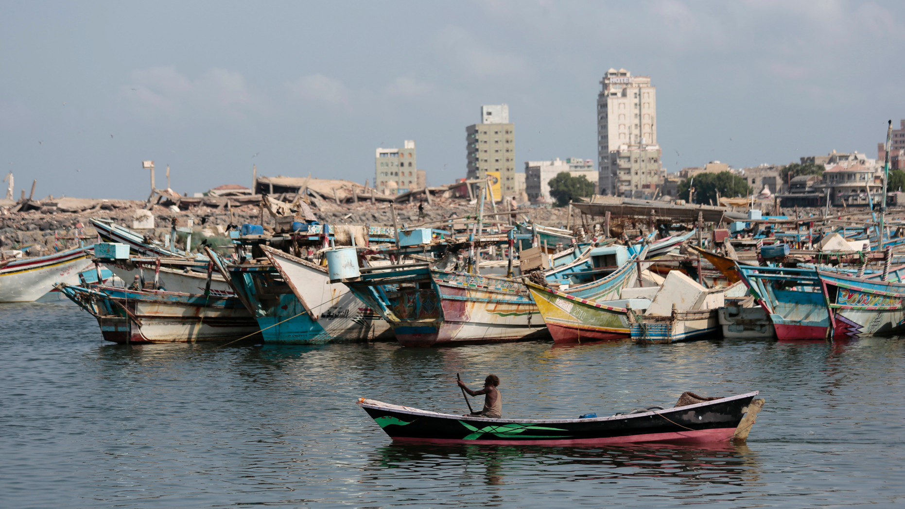 FILE - In this Friday Sept. 28, 2018 file photo, a fisherman paddles his boat past destroyed buildings on the coast of the port city of Hodeida, Yemen. Amnesty International said warned late Wednesday. Nov. 7, 2018 that Yemen's rebels have taken up positions on a hospital rooftop in the contested Red Sea city of Hodeida that a Saudi-led coalition is trying to capture. This raises concerns the Shiite rebels, known as Houthis, plan to use the patients at the Hodeida hospital as human shields to ward off airstrikes from the coalition. Amnesty is urging the warring sides to protect civilians. (AP Photo/Hani Mohammed, File)