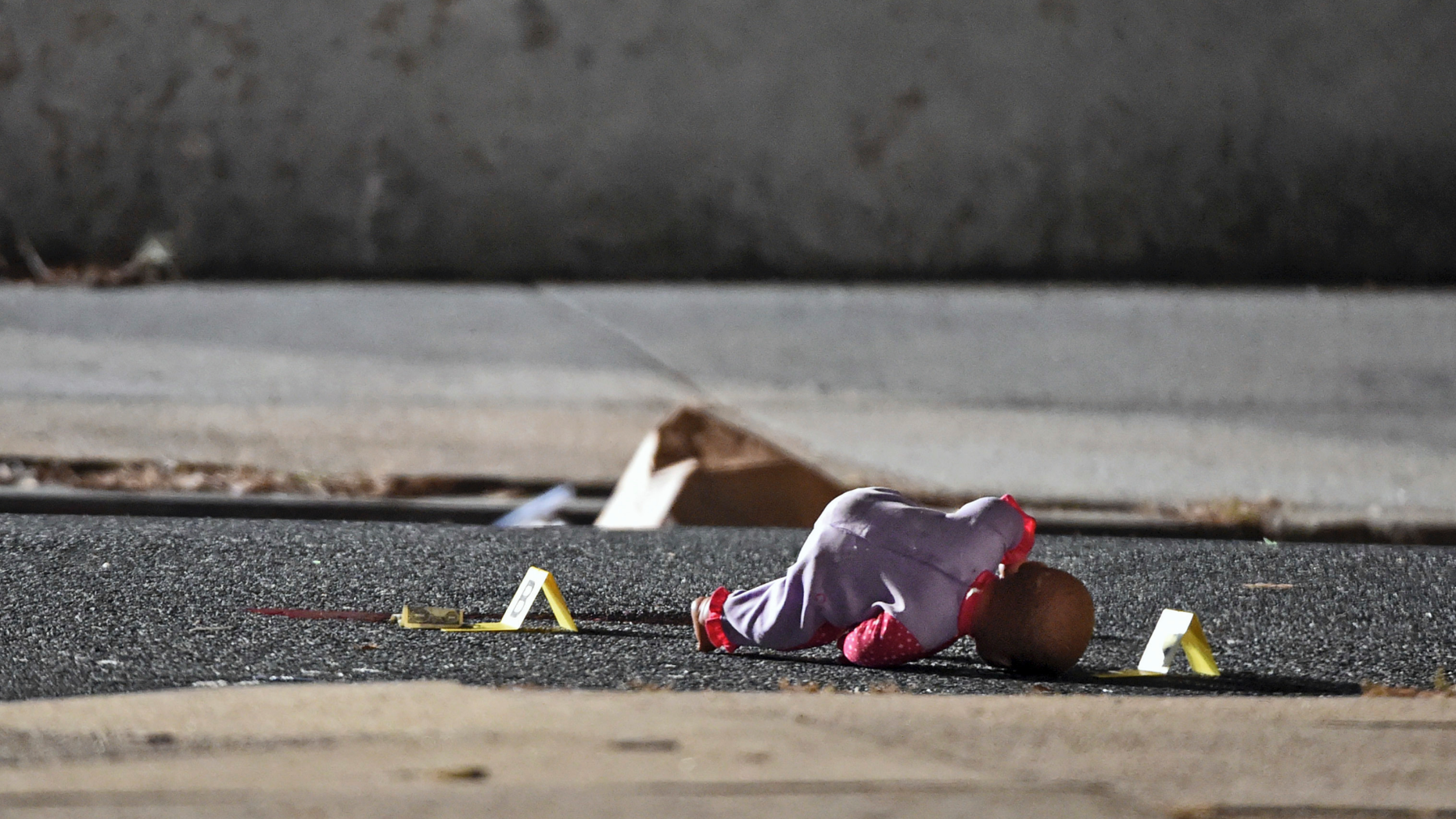 In this Monday, Nov. 19, 2018, photo, a child's doll lays next to police shooting evidence tags, as Baltimore City Police officers investigate the scene of a shooting at the 1000 block of McKean Avenue in Baltimore, where authorities say a 5-year-old girl was shot and wounded. The child l was to the hospital and immediately taken into surgery. Police were told she was alert and able to talk to doctors (Kenneth K. Lam/The Baltimore Sun via AP)