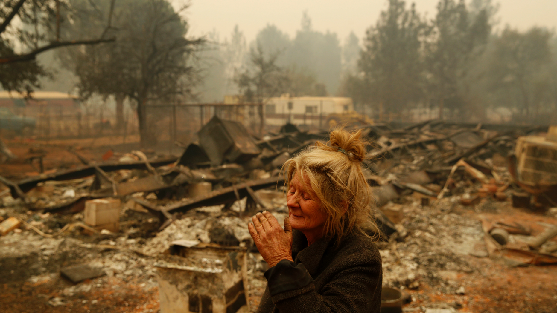 Cathy Fallon reacts as she stands near the charred remains of her home, Friday, Nov. 9, 2018, in Paradise, Calif. "I'll be darned if I'm going to let those horses burn in the fire," said Fallon, who stayed on her property to protect her 14 horses, all of which survived. (AP Photo/John Locher)