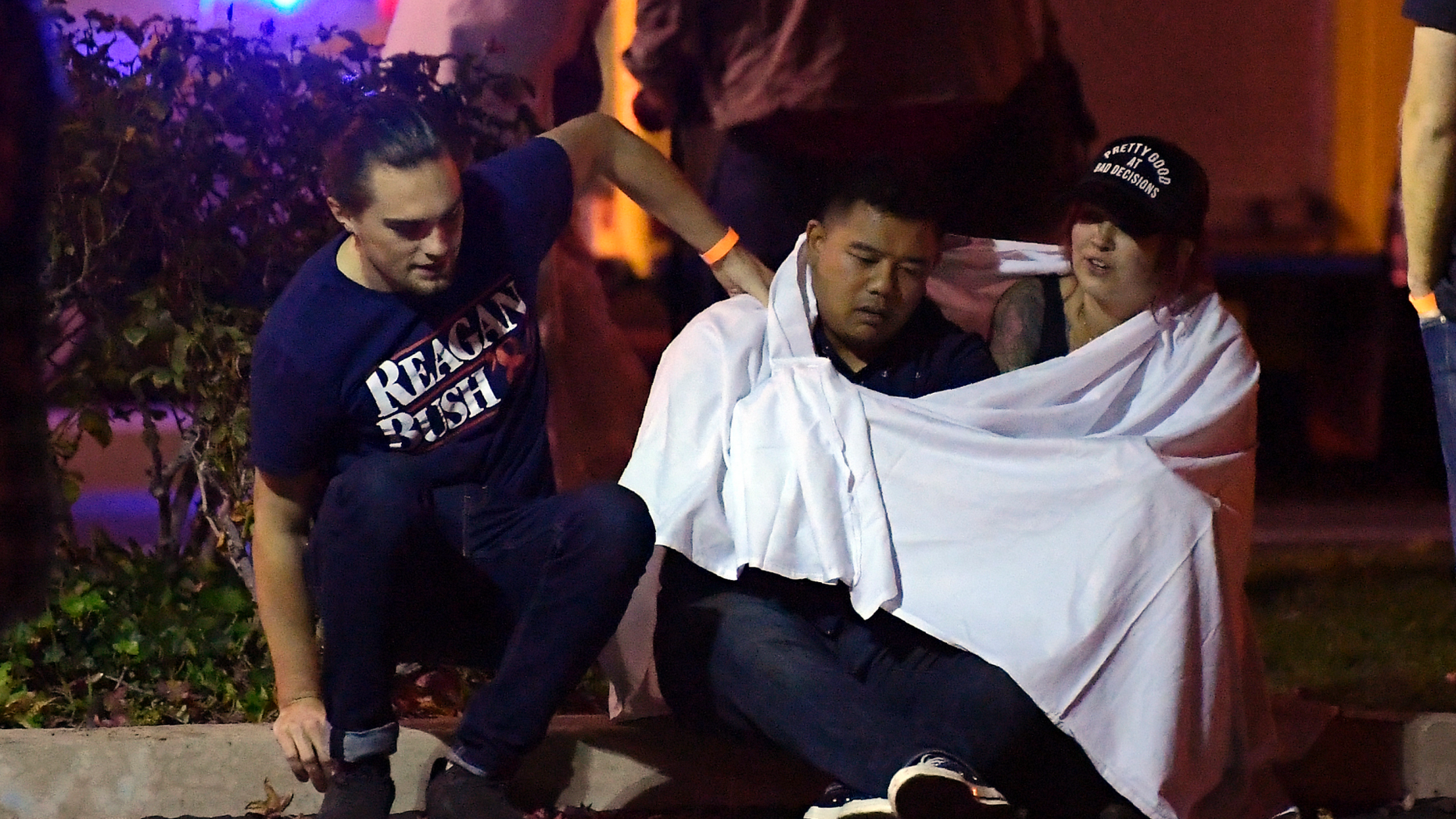 People comfort each other as they sit near the scene Thursday, Nov. 8, 2018, in Thousand Oaks, Calif. where a gunman opened fire Wednesday inside a country dance bar crowded with hundreds of people on "college night," wounding 11 people including a deputy who rushed to the scene. Ventura County sheriff's spokesman says gunman is dead inside the bar. (AP Photo/Mark J. Terrill)
