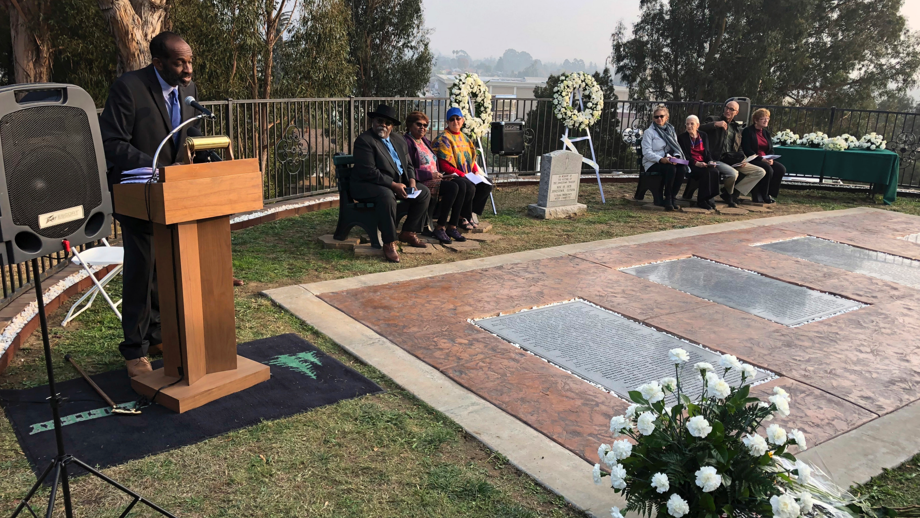 Jim Jones Jr., the adopted black son of the Rev. Jim Jones, speaks to a service for the 40th Jonestown anniversary at Evergreen Cemetery in Oakland, Calif., Sunday, Nov. 18, 2018. Ceremonies at the California cemetery marked the mass murders and suicides 40 years ago of 900 Americans orchestrated by the Rev.Jones at a jungle settlement in Guyana, South America. (AP Photo/Tim Reiterman)