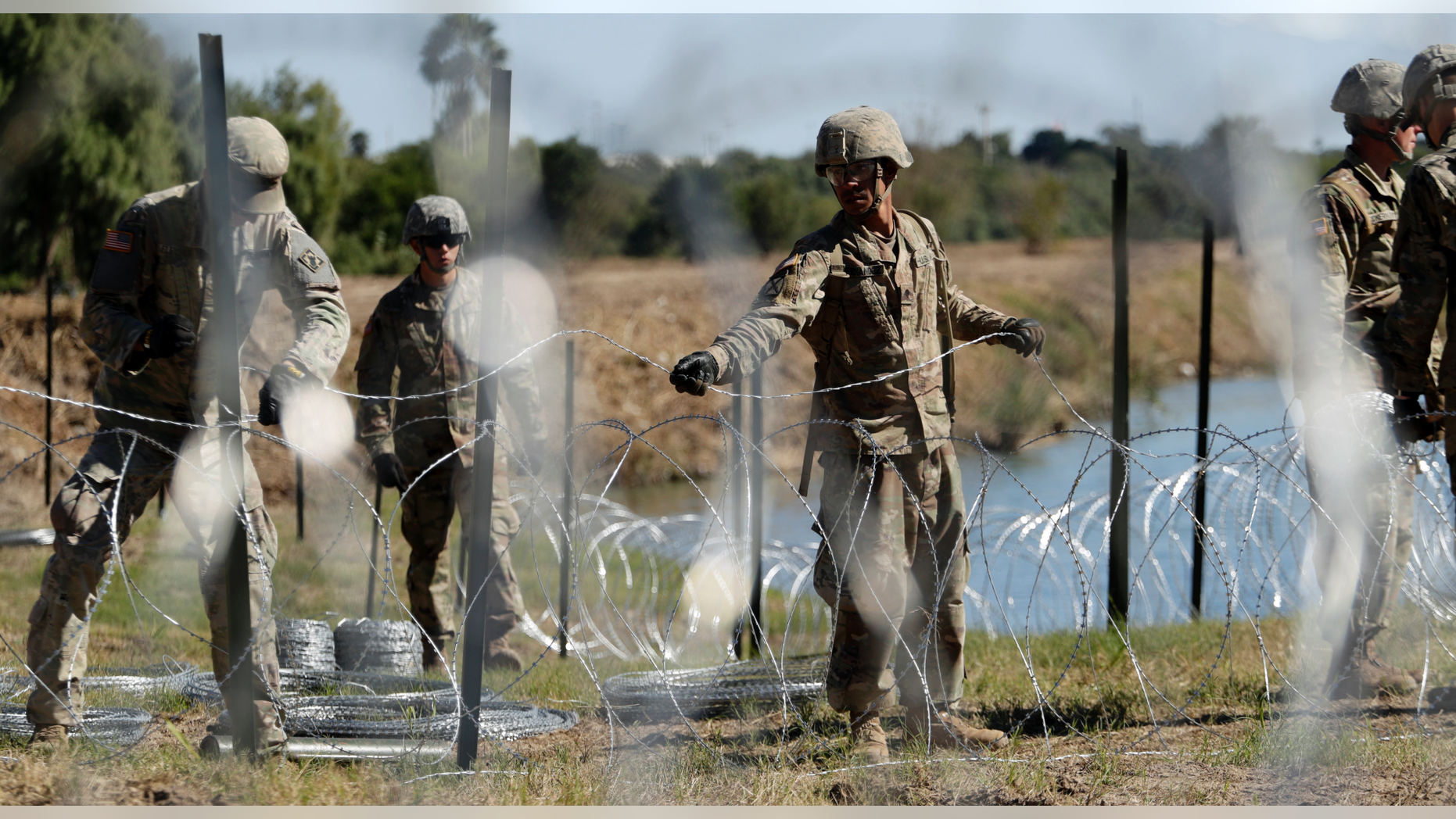 FILE - In this Nov. 16, 2018, photo, members of the U.S. military install multiple tiers of concertina wire along the banks of the Rio Grande near the Juarez-Lincoln Bridge at the U.S.-Mexico border in Laredo, Texas. The Pentagon is estimating the cost of the military's mission on the U.S.-Mexico border will be about $210 million under current plans. (AP Photo/Eric Gay)
