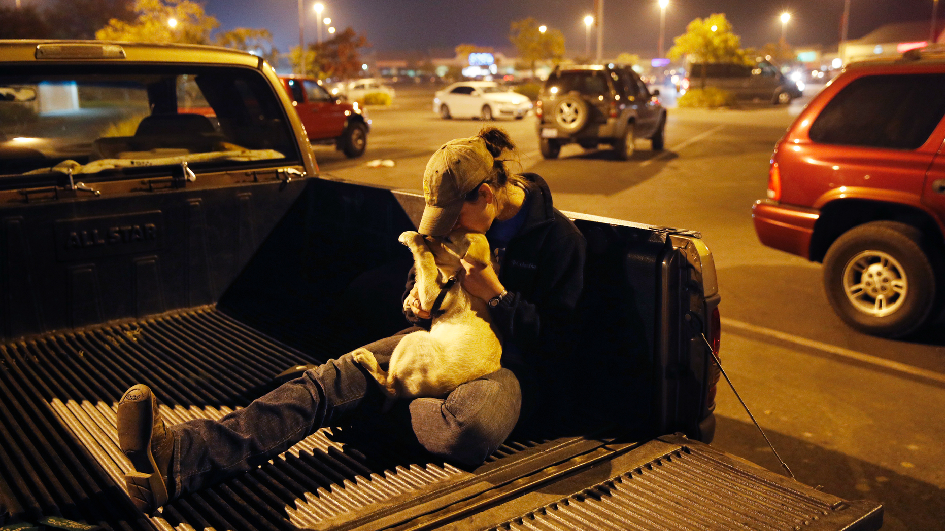 Sarah Gronseth kisses her dog Branch in the bed of a truck in a parking lot, Tuesday, Nov. 13, 2018, in Chico Calif. Gronseth, a teacher, evacuated some of her high school students in her truck as the fire bore down on the high school in Paradise, Calif. She lost her home in the fire. (AP Photo/John Locher)