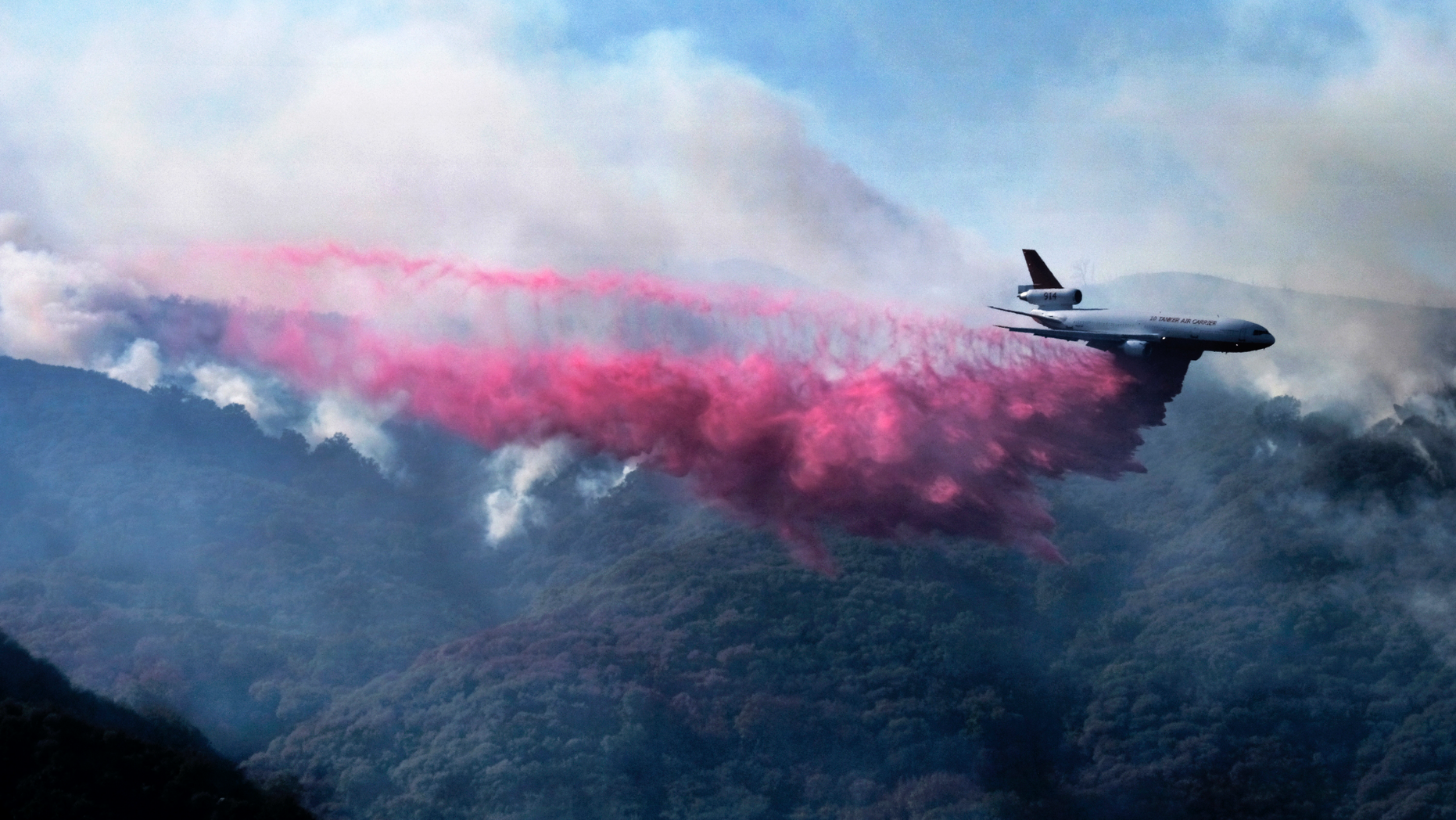 A firefighting DC-10 makes a fire retardant drop over a wildfire in the mountains near Malibu Canyon Road in Malibu, Calif. on Sunday, Nov. 11, 2018. Strong Santa Ana winds have returned to Southern California, fanning a huge wildfire that has scorched a string of communities west of Los Angeles. A one-day lull in the dry, northeasterly winds ended Sunday morning and authorities warn that the gusts will continue through Tuesday. (AP Photo/Richard Vogel)