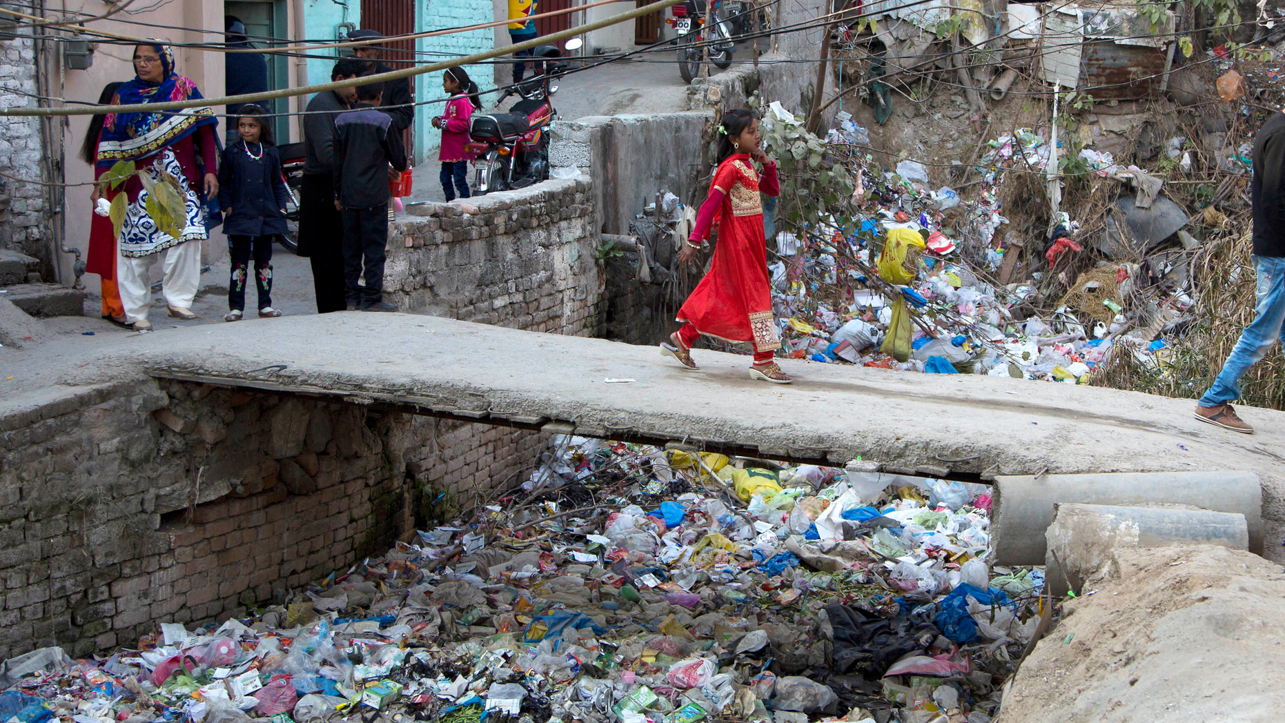FILE - In this Dec. 25, 2016, file photo, a Pakistani Christian girl crosses a bridge in poor Christian neighborhood in Islamabad, Pakistan.The uproar surrounding Aasia Bibi _ a Pakistani Christian woman who was acquitted of blasphemy charges and released from death row but remains in isolation for her protection _ has drawn attention to the plight of the country's Christians.The minority, among Pakistan's poorest, has faced an increasingly intolerant atmosphere in this Muslim-majority nation where radical religious and sectarian groups have become more prominent in recent years. (AP Photo/B.K. Bangash, File)