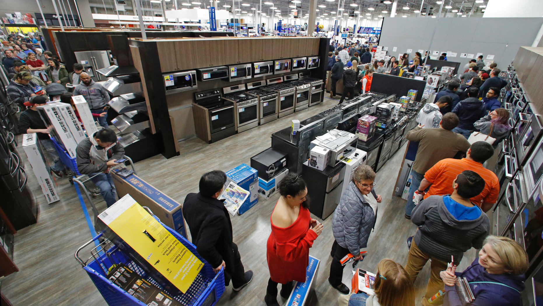 FILE- In this Nov. 22, 2018, file photo people line up to pay for their purchases as they shop during an early Black Friday sale at a Best Buy store on Thanksgiving Day in Overland Park, Kan. On Thursday, Nov. 29, the Conference Board releases its November index on U.S. consumer confidence. (AP Photo/Charlie Riedel, File)