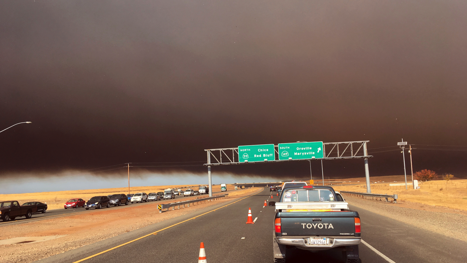 Smoke from the Camp Fire, burning in the Feather River Canyon near Paradise, Calif., darkens the sky as seen from Highway 99 near Marysville, Calif., Thursday, Nov. 8, 2018. (AP Photo/Don Thompson)