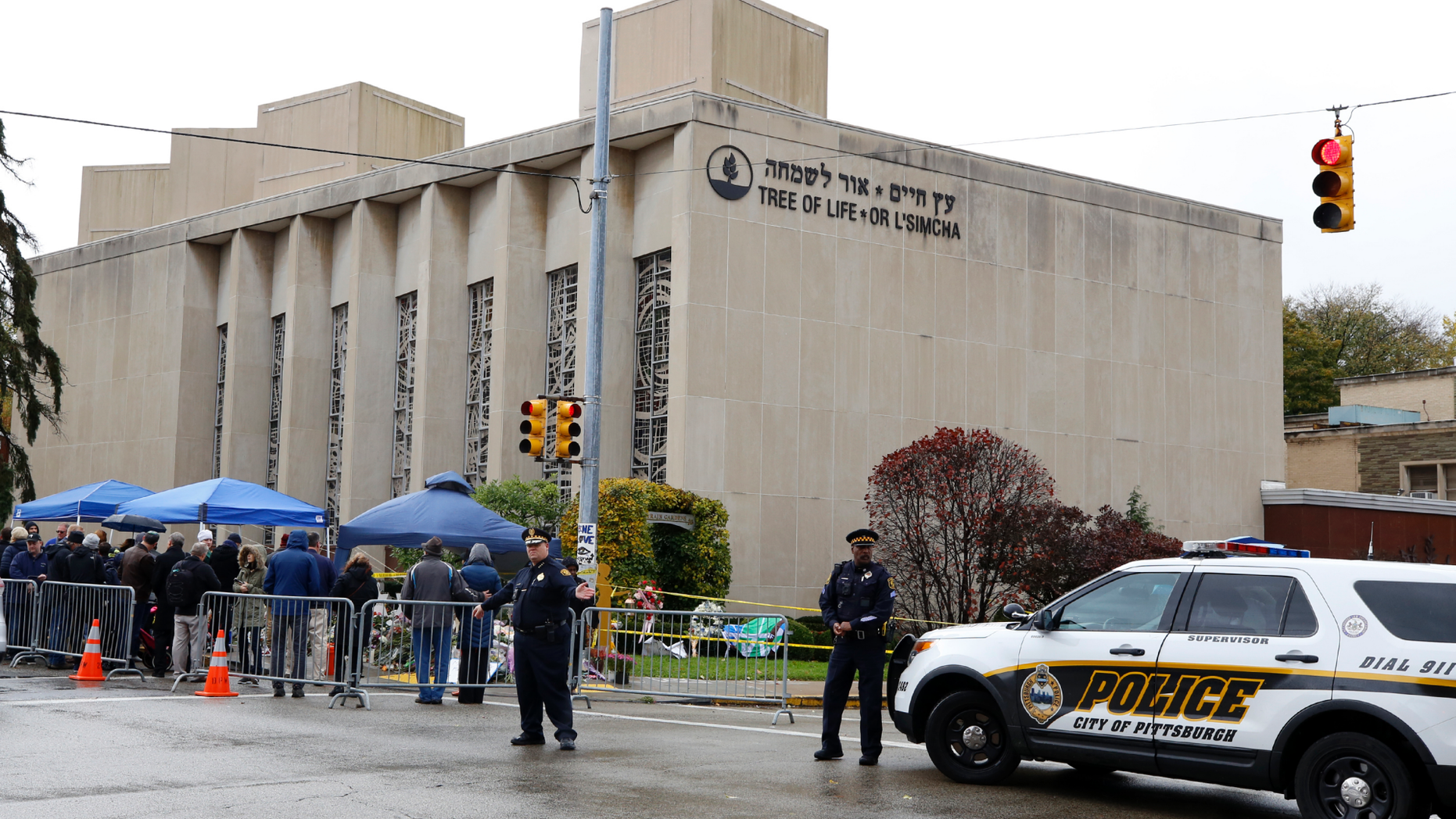 Pittsburgh Police direct traffic as their vehicles close the street adjacent to the Tree of Life Synagogue on Saturday Nov. 3 2018 as a curbside Shabbat morning service is held on the street corner in the Squirrel Hill neighborhood of Pittsburgh. The