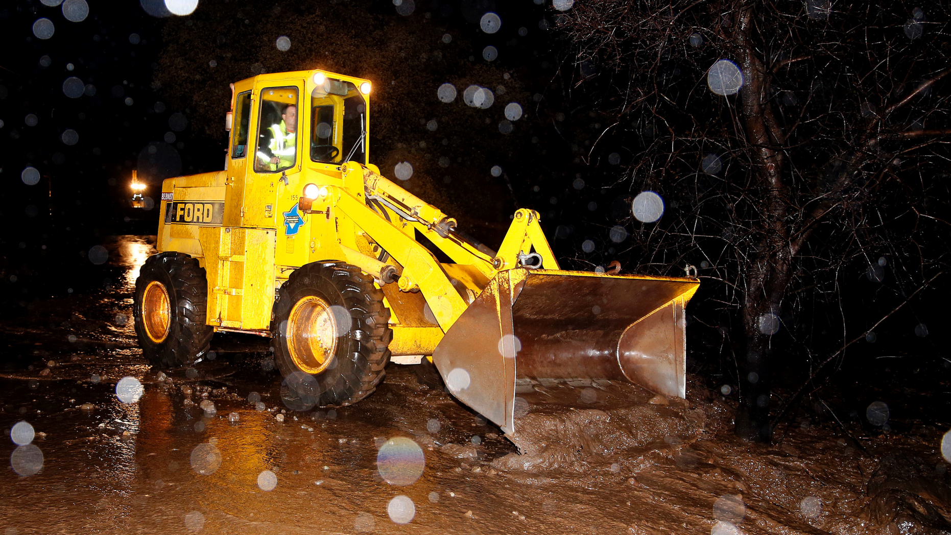A scoop clears debris from a mudslide that partially blocked Honey Run Road, Thursday, Nov. 29, 2018, near Chico, Calif. Flash flooding hit Chico and nearby wildfire-scarred Paradise, forcing officials to deploy swift water rescue teams to save people stuck in vehicles and rescue them from homes. (AP Photo/Rich Pedroncelli)