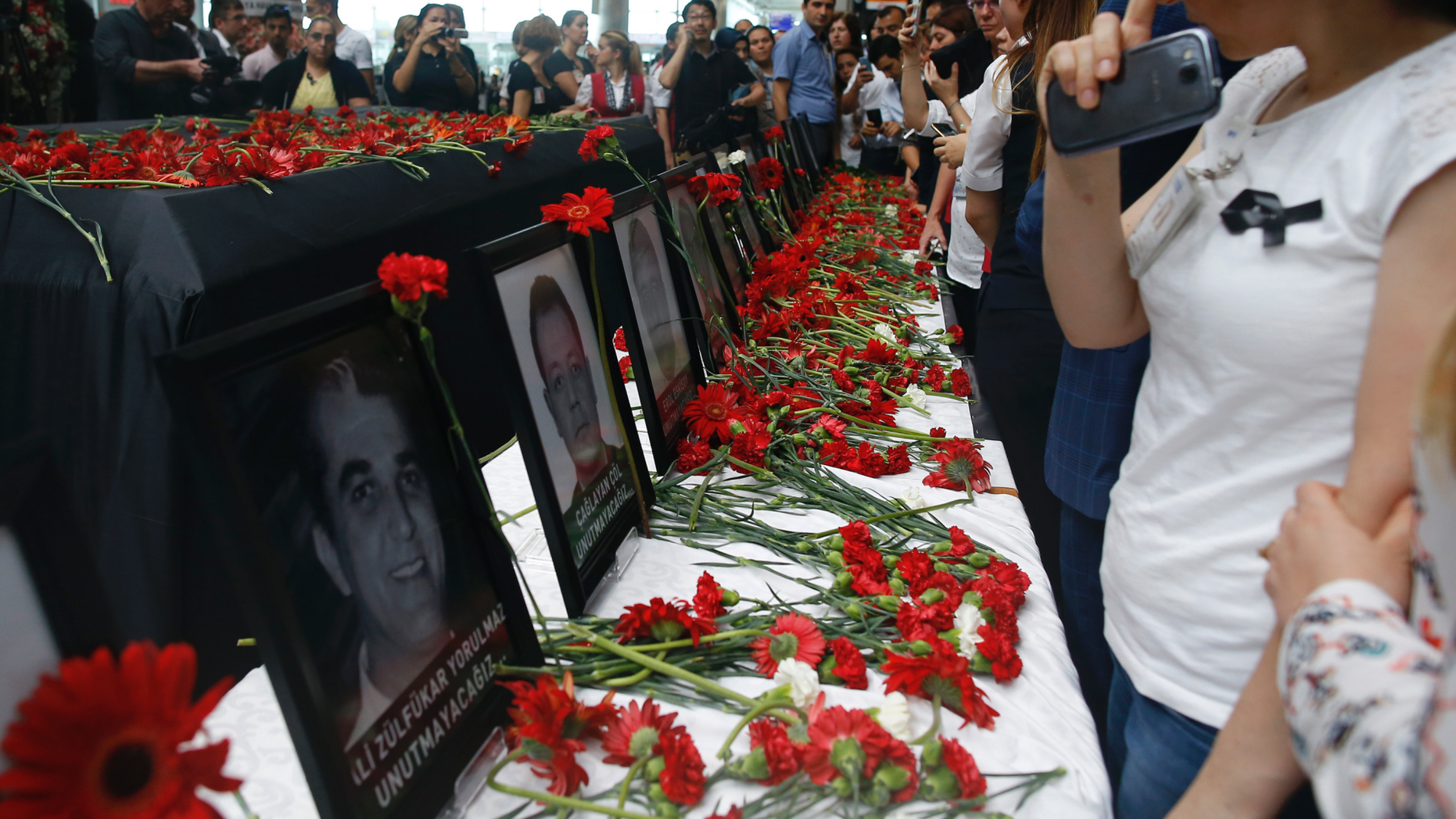 FILE _ in this file photo dated Thursday, June 30, 2016, Photographs of victims of an attack at Istanbul's Ataturk Airport are displayed among flower tributes as family members, colleagues and friends gather for a memorial ceremony at the Ataturk Airport in Istanbul. A court in Istanbul convicted six people and sentenced them to life in prison for involvement in the 2016 extremist attack at Istanbul's main airport that killed 45 people, Turkey’s state-run Anadolu Agency reported Friday Nov. 16, 2018. (AP Photo/Emrah Gurel, FILE)