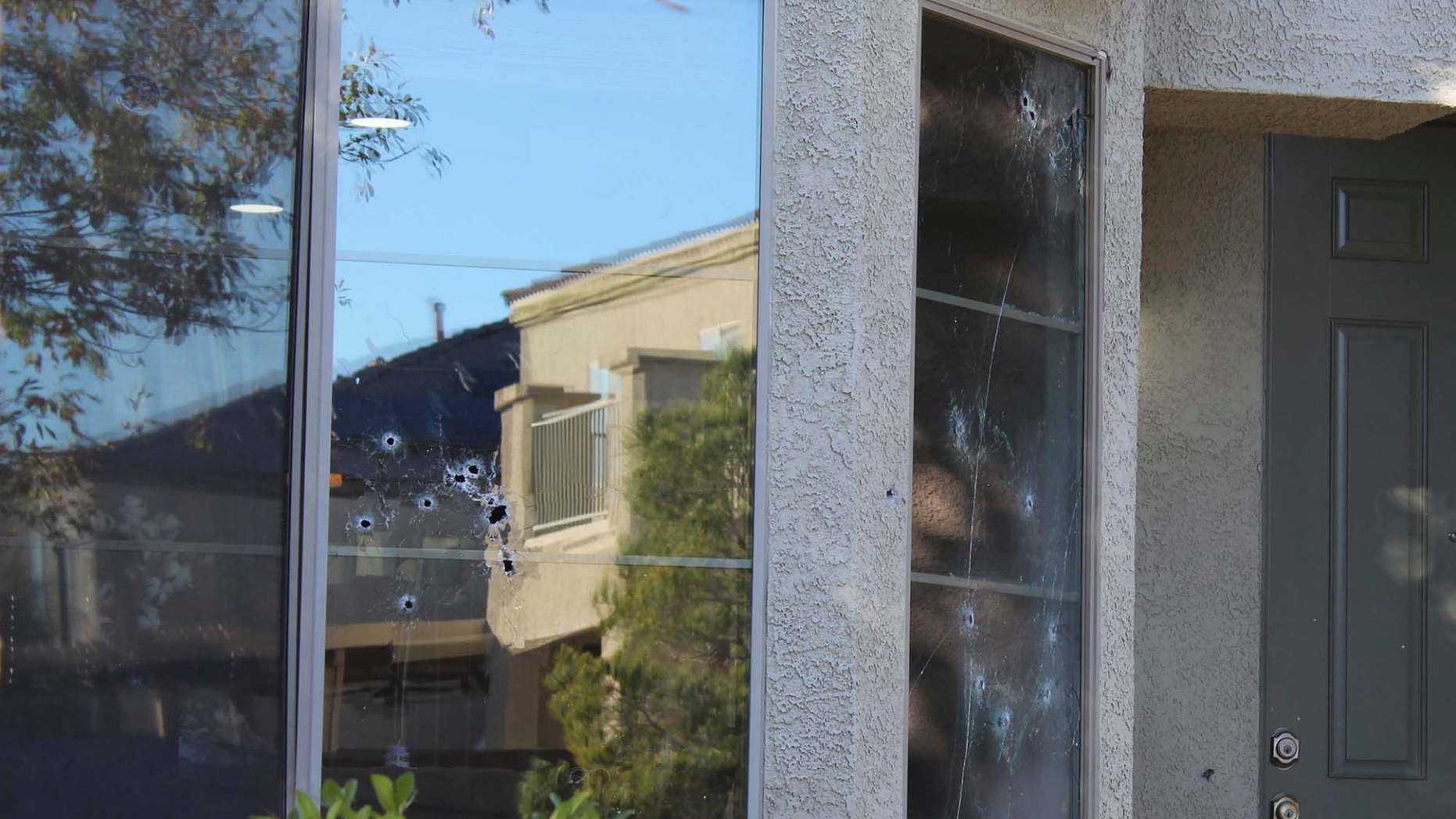 Bullet holes mark the windows of a house that was hit by gunfire Thursday night, killing an 11-year-old girl in North Las Vegas, Friday, Nov. 2, 2018. An armed group intent on gang-related retaliation opened fire on the wrong house in suburban Las Vegas, killing the girl in her kitchen, police said Friday. (Max Michor/Las Vegas Review-Journal via AP)