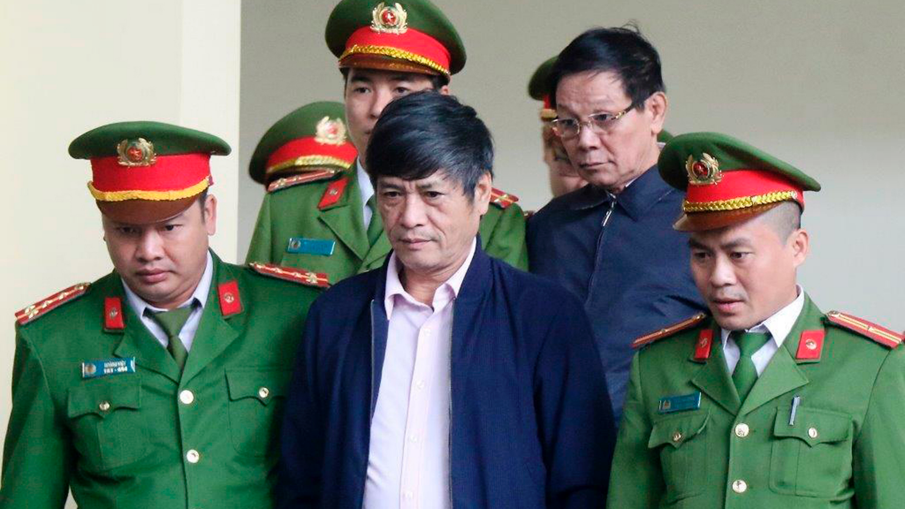 Former police generals Nguyen Thanh Hoa, center front row, and Phan Van Vinh, right second row, are escorted by police to a courtroom of People's Court in northern province of Phu Tho, Vietnam, Friday, Nov. 30, 2018. The court jailed the two former police generals for protecting a multimillion-dollar online gambling ring as the Communist government steps up its crackdown on graft. Former national police chief Phan and former head of hi-tech crimes police department Nguyen were sentenced to nine and 10 years respectively after being convicted of abuse of power at the end of the three-week trial. (Nguyen Trung Kien/Vietnam News Agency via AP)