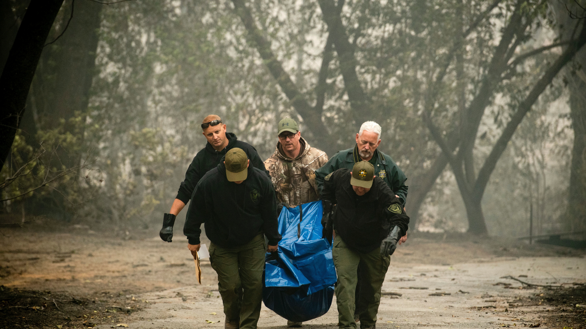FILE - In this Nov. 10, 2018, file photo, sheriff's deputies recover the remains of a victim of the Camp Fire in Paradise, Calif. The massive wildfire that killed dozens of people and destroyed thousands of homes has been fully contained after burning for more than two weeks, authorities said Sunday, Nov. 25. (AP Photo/Noah Berger, File)