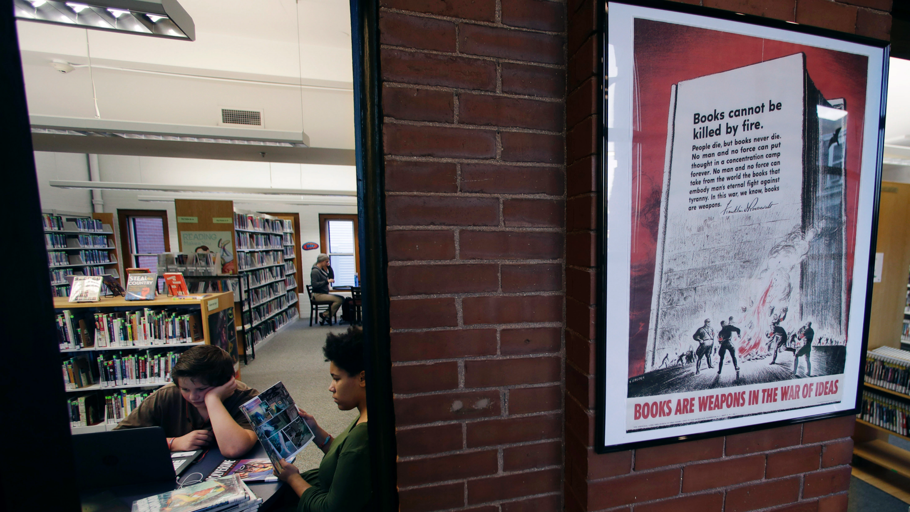 A 1942 Office of War Information poster copy hangs in a hallway of the Rochester Public Library in Rochester, N.H., Thursday, Nov. 8, 2018. A trove of propaganda posters from World War I and II were found recently found after being lost in storage for decades in the library's basement. (AP Photo/Charles Krupa)