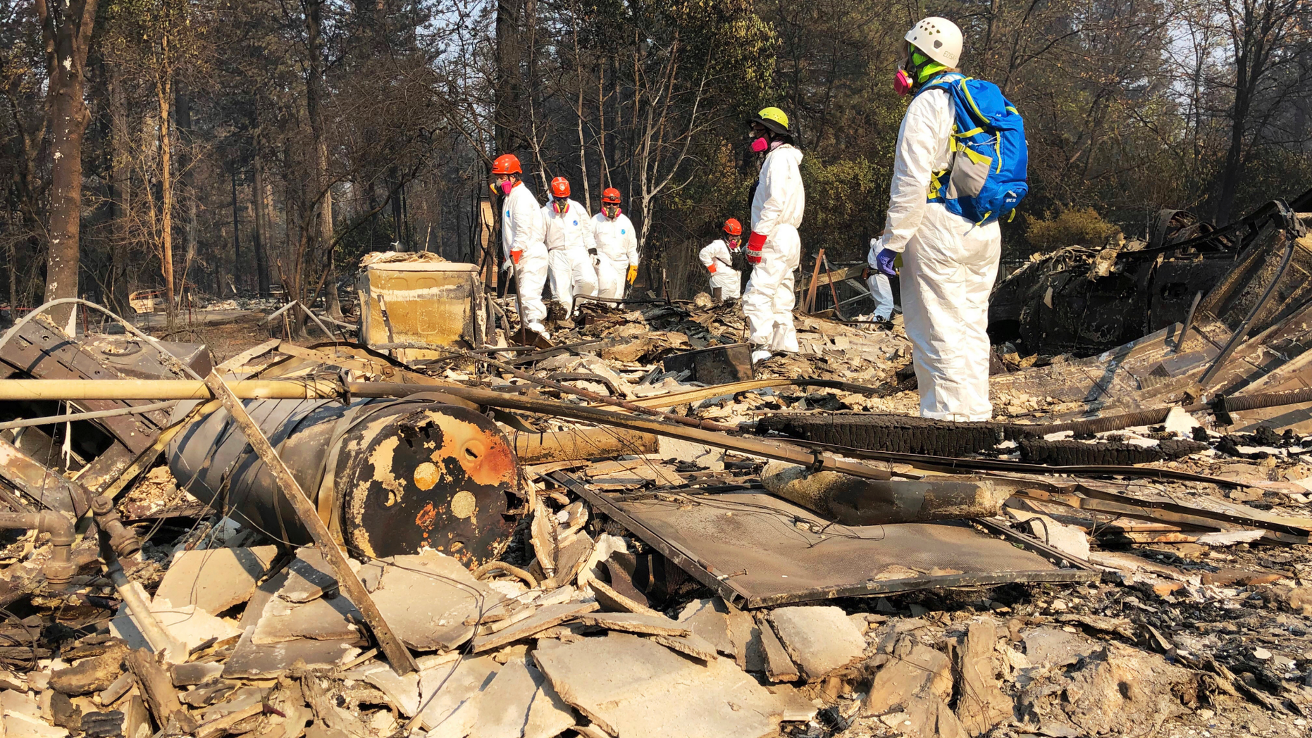 File - In this Nov. 18, 2018 file photo, volunteer members of an El Dorado County search and rescue team search the ruins of a home, looking for human remains, in Paradise, Calif., following a wildfire. Authorities have deployed a powerful tool to aid in their race to identify the remains of 77 bodies burned in the deadly wildfire that ripped through Northern California: Rapid DNA testing that produces results in just two hours. But the technology that can match DNA to bone fragments in as little as two hours is only as effective as the numbers of people who show up to give a sample, and so far there are not nearly enough volunteers. (AP Photo/Sudhin Thanawala, File)