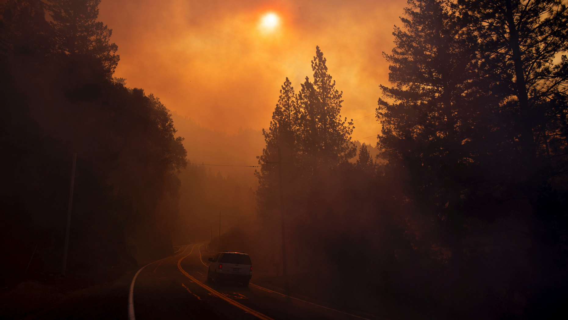 A vehicle drives through smoke from a wildfire near Pulga, Calif., Sunday, Nov. 11, 2018. (AP Photo/Noah Berger)