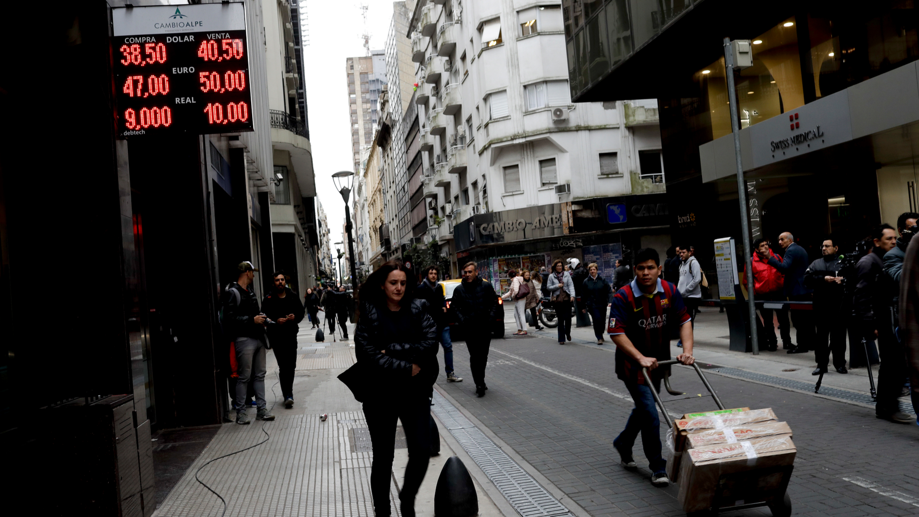 FILE - In this Aug. 30, 2018 file photo, people walk past an exchange house in Buenos Aires, Argentina. Argentina had hoped to show off its newly market-friendly economy to the world when the G-20 group of the world’s top economies begins its first South American summit in late November, but instead it’s looking for help to avoid an all-out crisis. (AP Photo/Natacha Pisarenko, File)