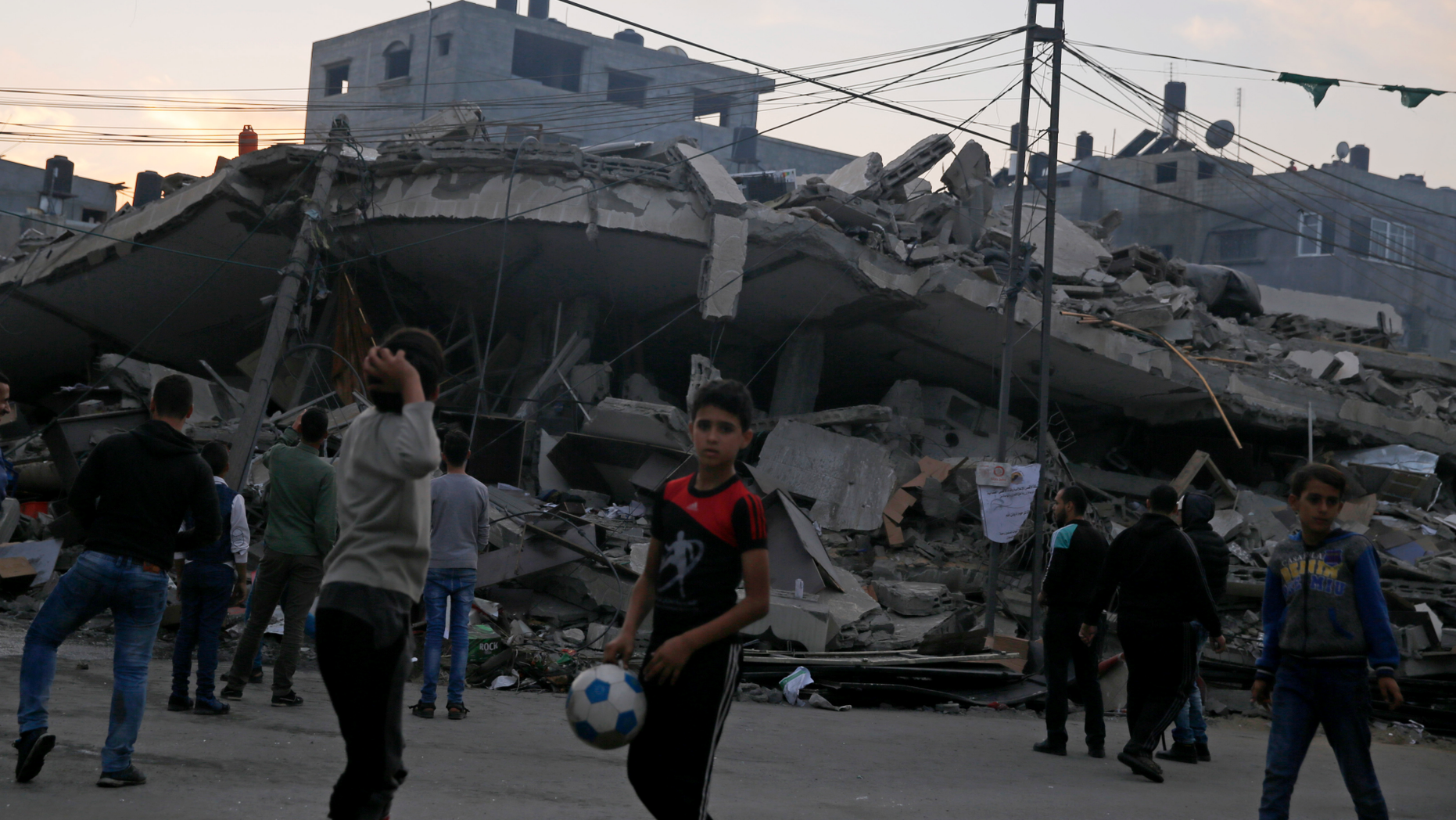 Palestinians gather in front of a destroyed building that was hit by Israeli airstrikes, in Gaza City, Tuesday, Nov. 13, 2018. (AP Photo/Hatem Moussa)