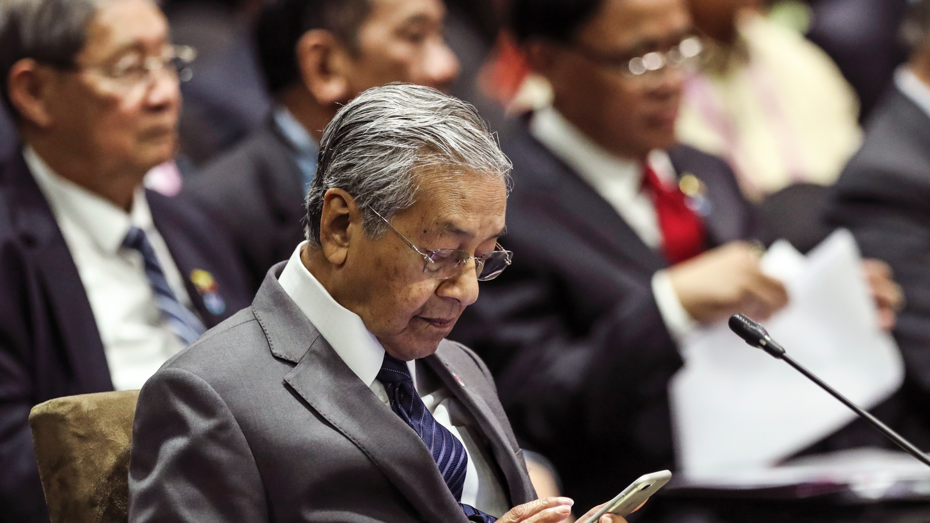 Malaysian Prime Minister Mahathir Mohamad uses his mobile phone during the 13th East Asian Summit Plenary on the sidelines of the 33rd ASEAN summit in Singapore, Thursday, Nov. 15, 2018. At 93, Malaysia’s comeback prime minister, Mahathir Mohamed, cuts a striking figure as the center of attention at a Southeast Asian summit in Singapore. (AP Photo/Yong Teck Lim)