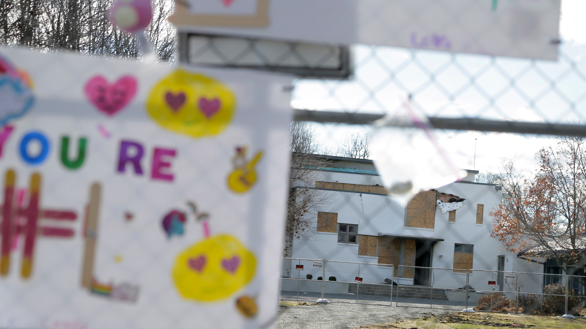 Tributes are hung on a fence in front of the house that was the site of a quadruple homicide in Colts Neck, N.J., Thursday, Nov. 29, 2018. Prosecutors say financial motives led a New Jersey technology executive to kill his brother, the brother's wife and their young children before setting fire to their two homes. (AP Photo/Seth Wenig)