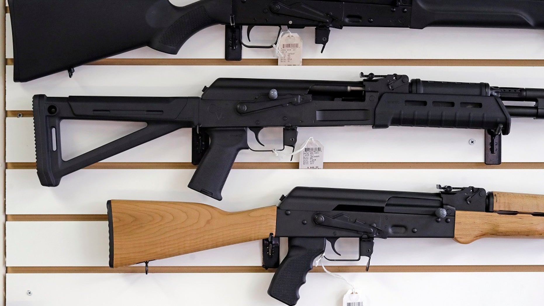 FILE - Semi-automatic rifles are displayed on a wall at a gun shop.