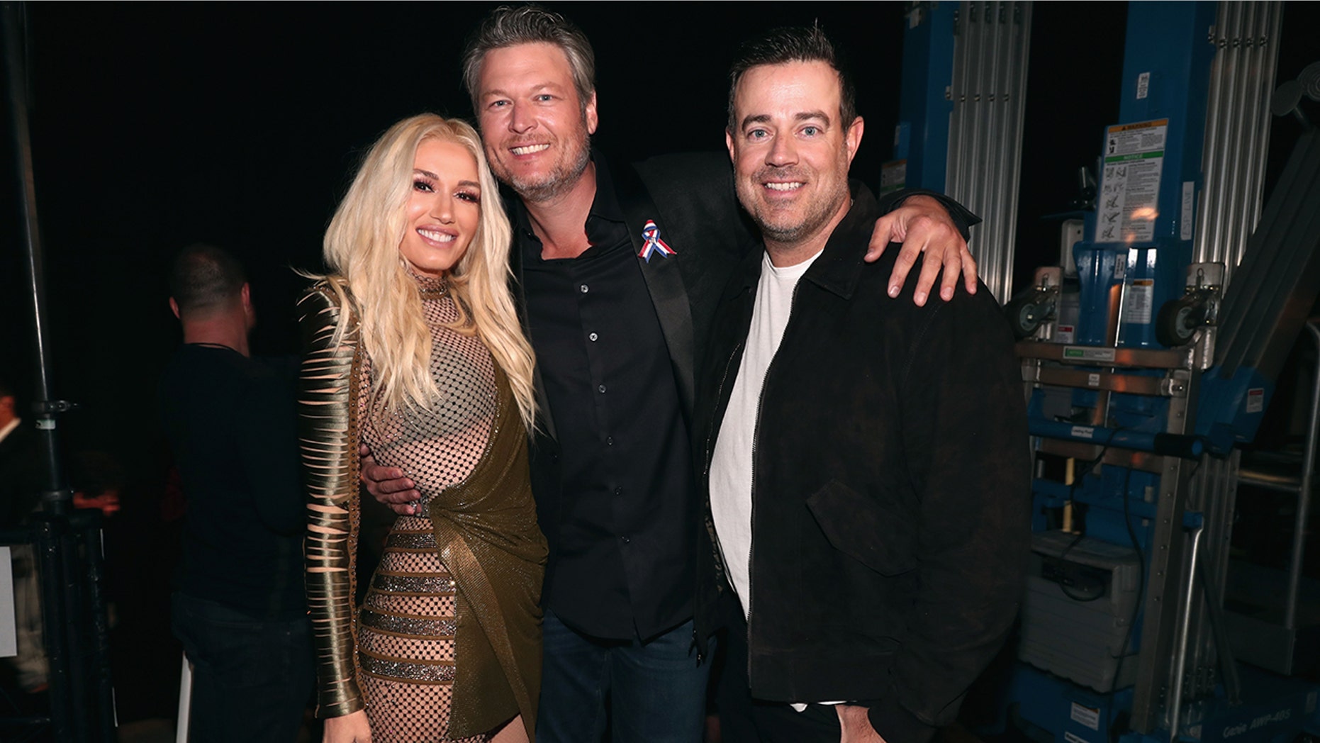 Pictured: (l-r) Recording artists-TV personalities Gwen Stefani and Blake Shelton and TV personality Carson Daly pose during the 2018 E! People's Choice Awards held at the Barker Hangar on November 11, 2018.