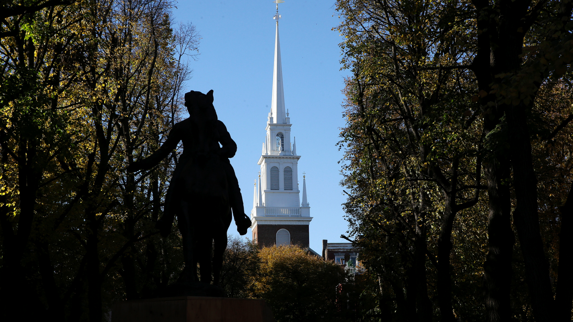In this Wednesday, Nov. 7, 2018 photo Old North Church stands behind a statue of Paul Revere in the North End neighborhood of Boston. A bronze wreath and plaque that forms part of a memorial, which includes thousands of dog tags honoring soldiers killed in Iraq and Afghanistan, has been installed on the grounds of the church. The new plaque and wreath help explain the meaning of the dog tags and acknowledge Britain's contribution and sacrifice. (AP Photo/Steven Senne)