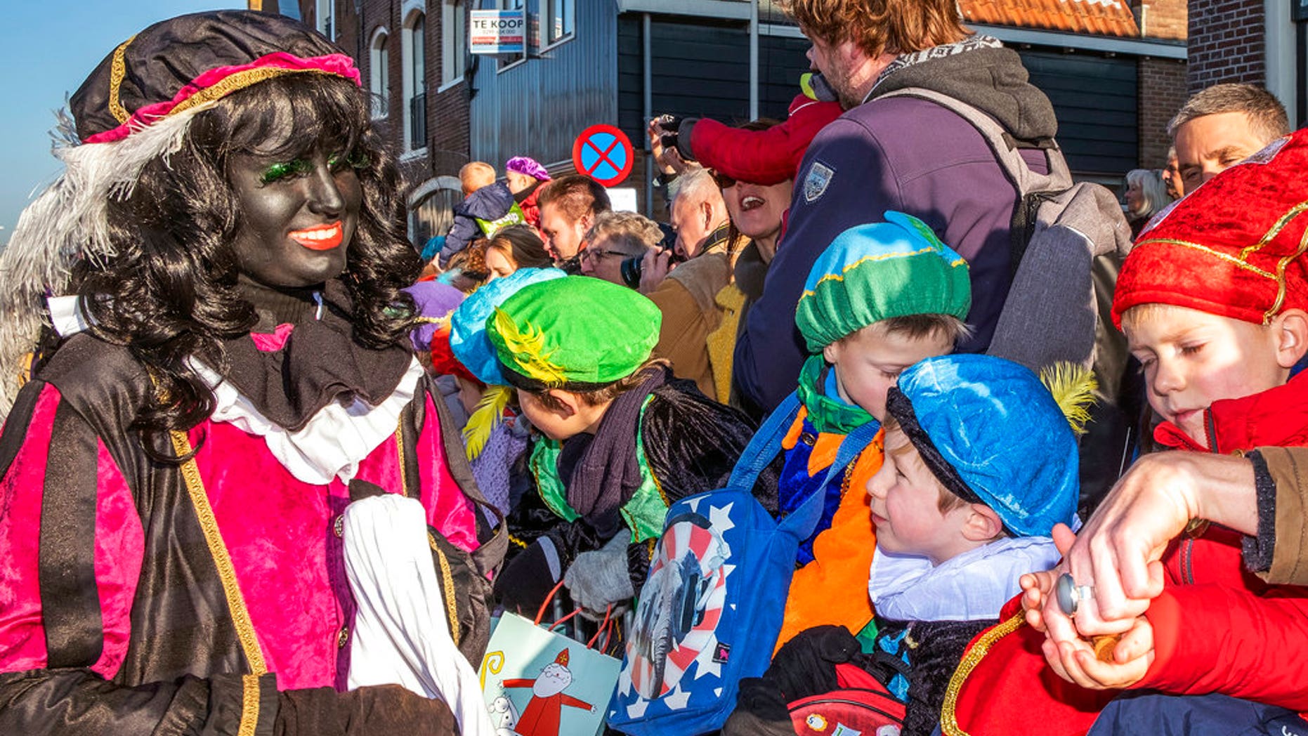 A Black Pete interacts with children during the arrival of Sinterklaas in Monnickendam, Netherlands, Saturday, Nov. 17, 2018. White people often daub their faces with black paint when they dress up to play the character. Opponents say such depictions of Black Pete promote racist stereotypes. Supporters defend the sidekick of Sinterklaas, the white-bearded, red-robed Dutch version of St. Nicholas, as a traditional children's character. (AP Photo/Patrick Post)