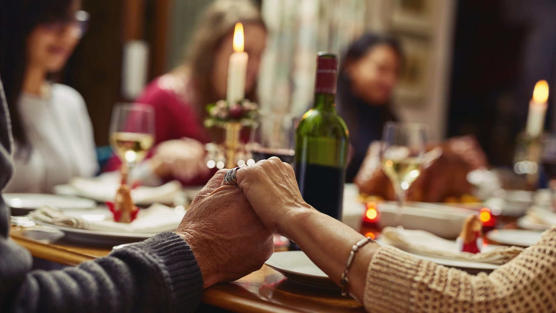 Closeup shot of people holding hands in prayer before having a meal together