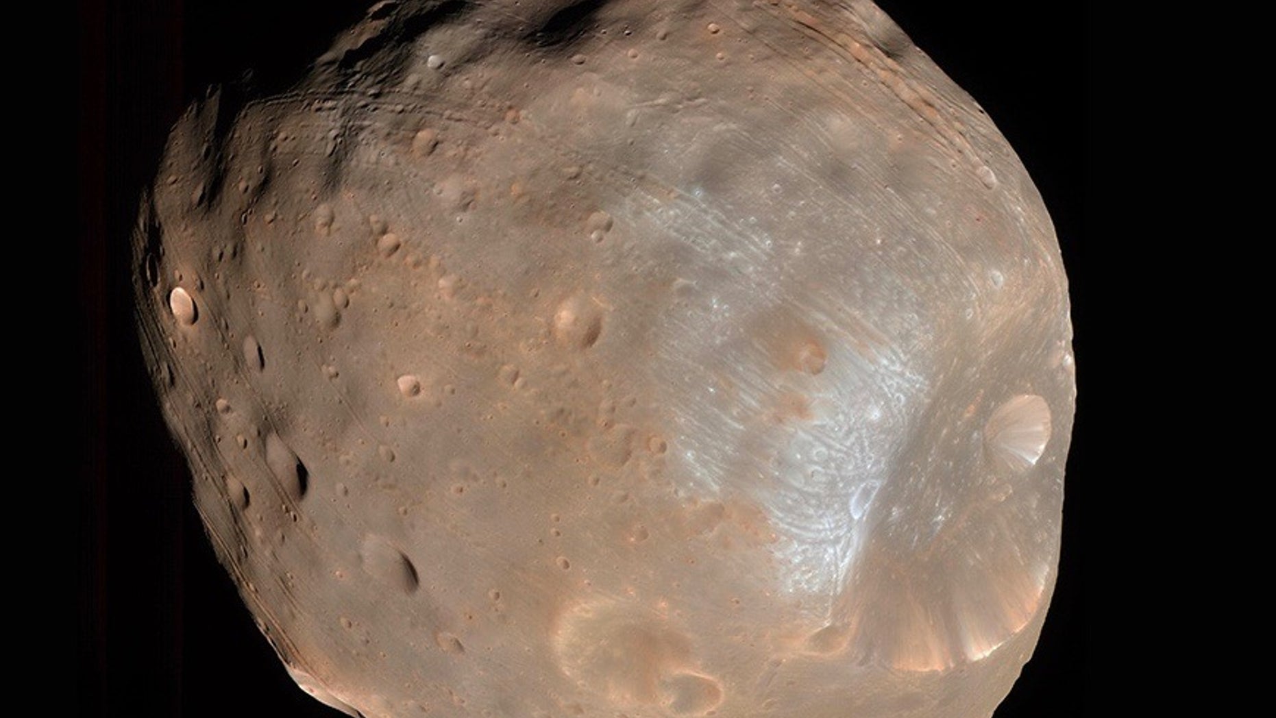 The strange grooves on the surface of the tiny Mars moon Phobos (seen here by NASA's Mars Reconnaissance Orbiter) were made by rolling boulders knocked loose by a giant impact, a new study suggests.