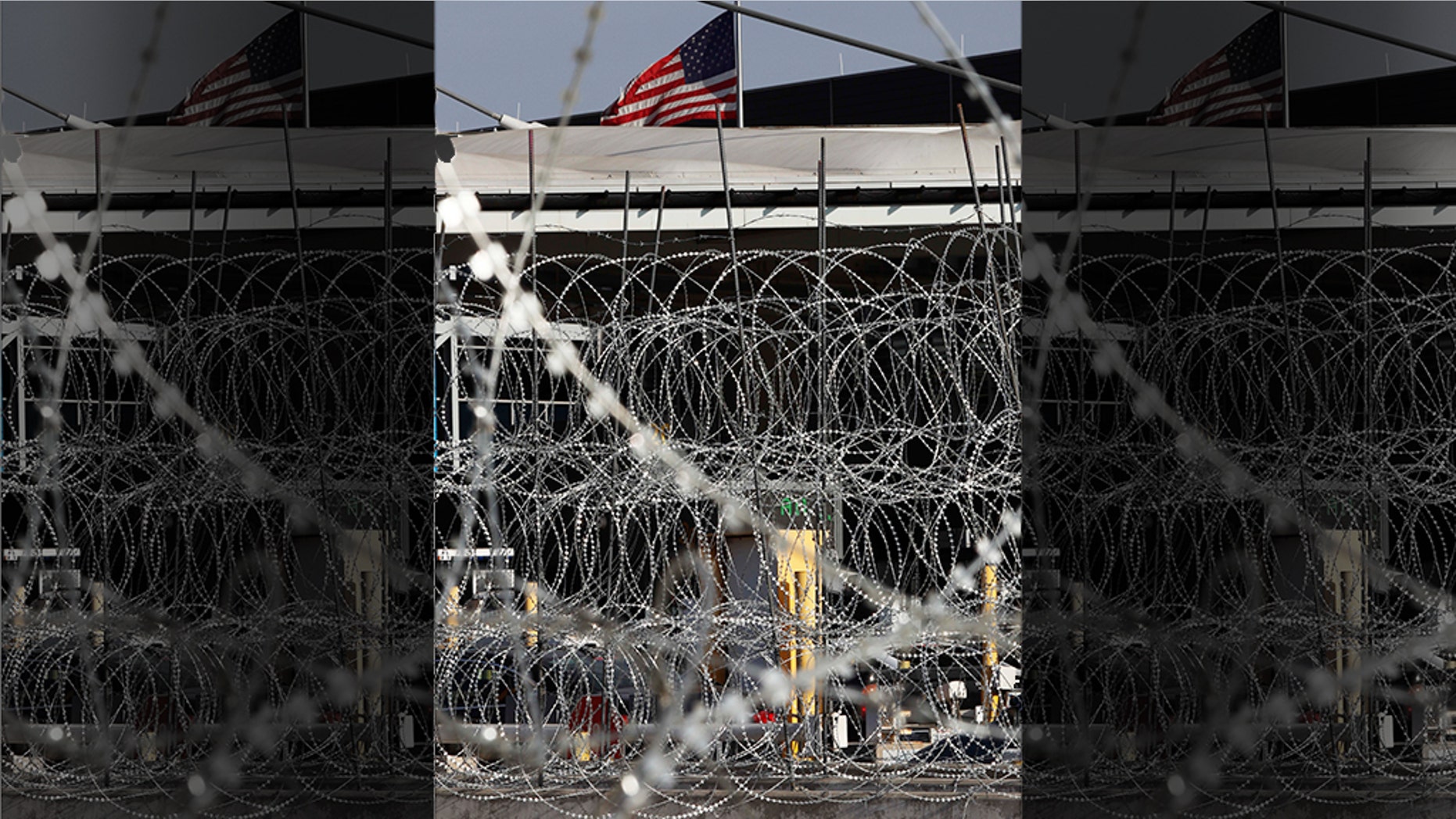 Newly placed barbed wires hangs at the U.S. border fence, where a U.S. flag flies in San Ysidro, seen from Tijuana, Mexico, Monday. The United States closed off northbound traffic for several hours at the busiest border crossing with Mexico to install new security barriers on Monday, a day after hundreds of Tijuana residents protested against the presence of thousands of Central American migrants. (AP Photo/Marco Ugarte)