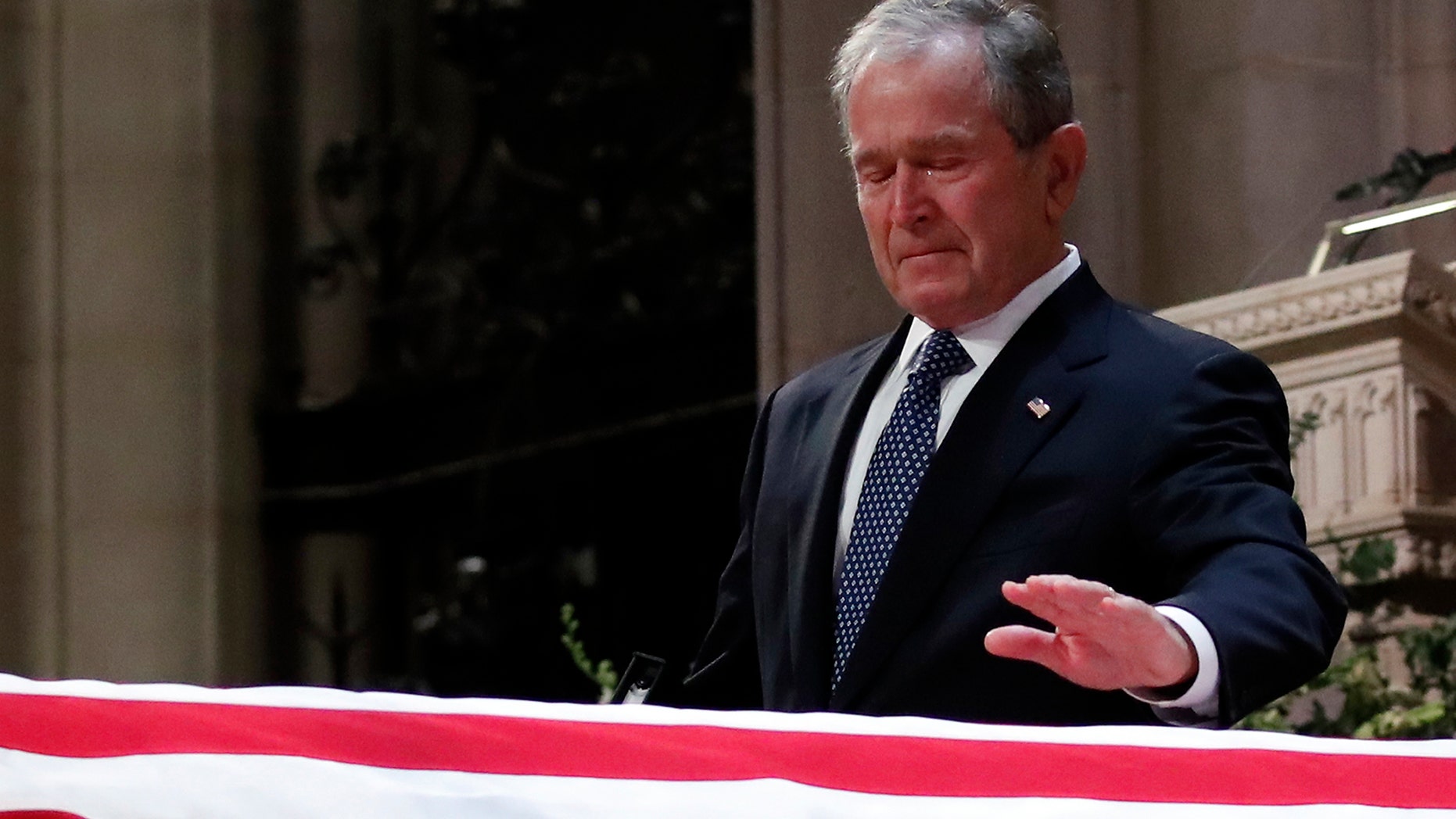 Former President George W. Bush touches the casket of his father, former President George H.W. Bush, at the State Funeral at the National Cathedral, Wednesday, Dec. 5, 2018, in Washington. (AP Photo/Alex Brandon, Pool)