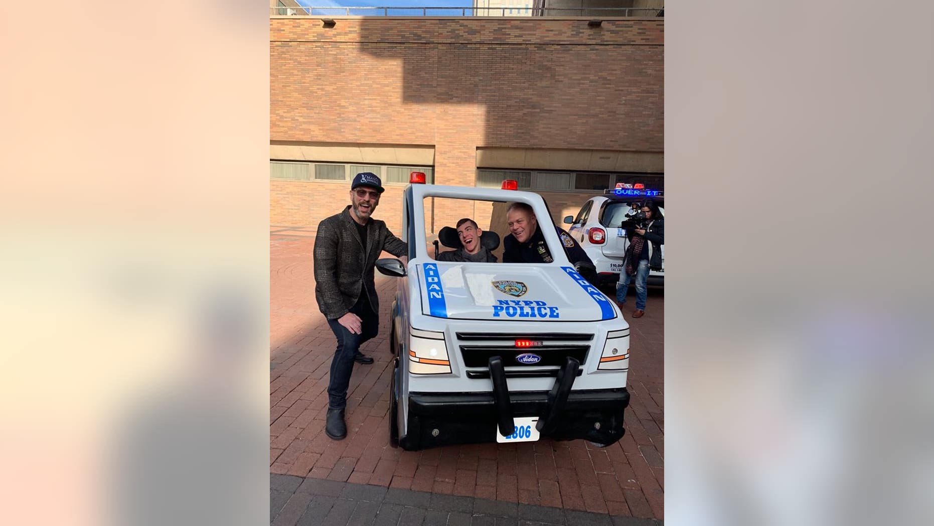Aidan Riley, pictured with his police officer father and David Vogel, regional director of Magic Wheelchair, received his customized car on Wednesday.