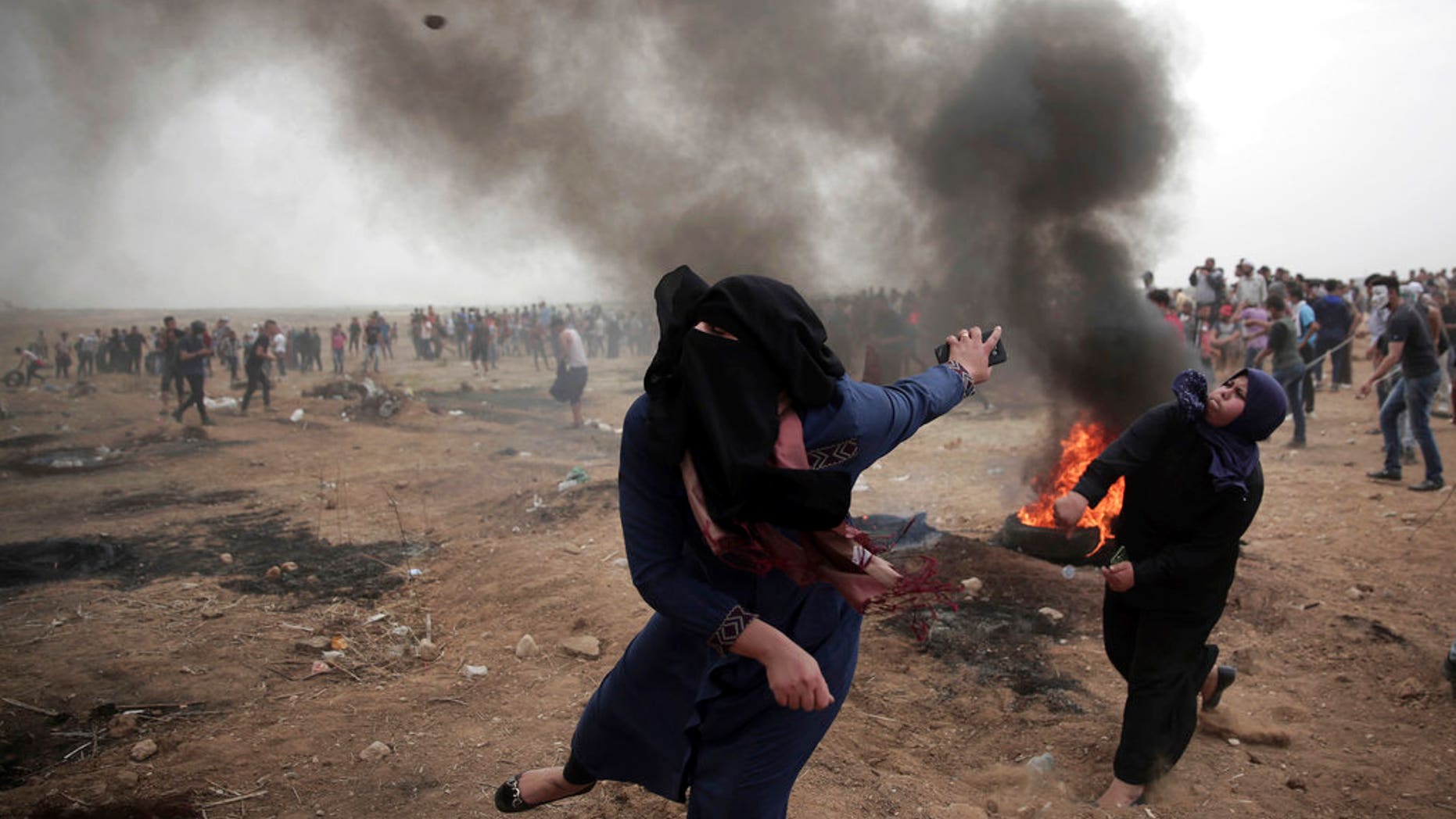 Palestinian women hurl stones at Israeli troops during a protest at the Gaza Strip's border with Israel on May 4, 2018. (AP Photo/ Khalil Hamra)
