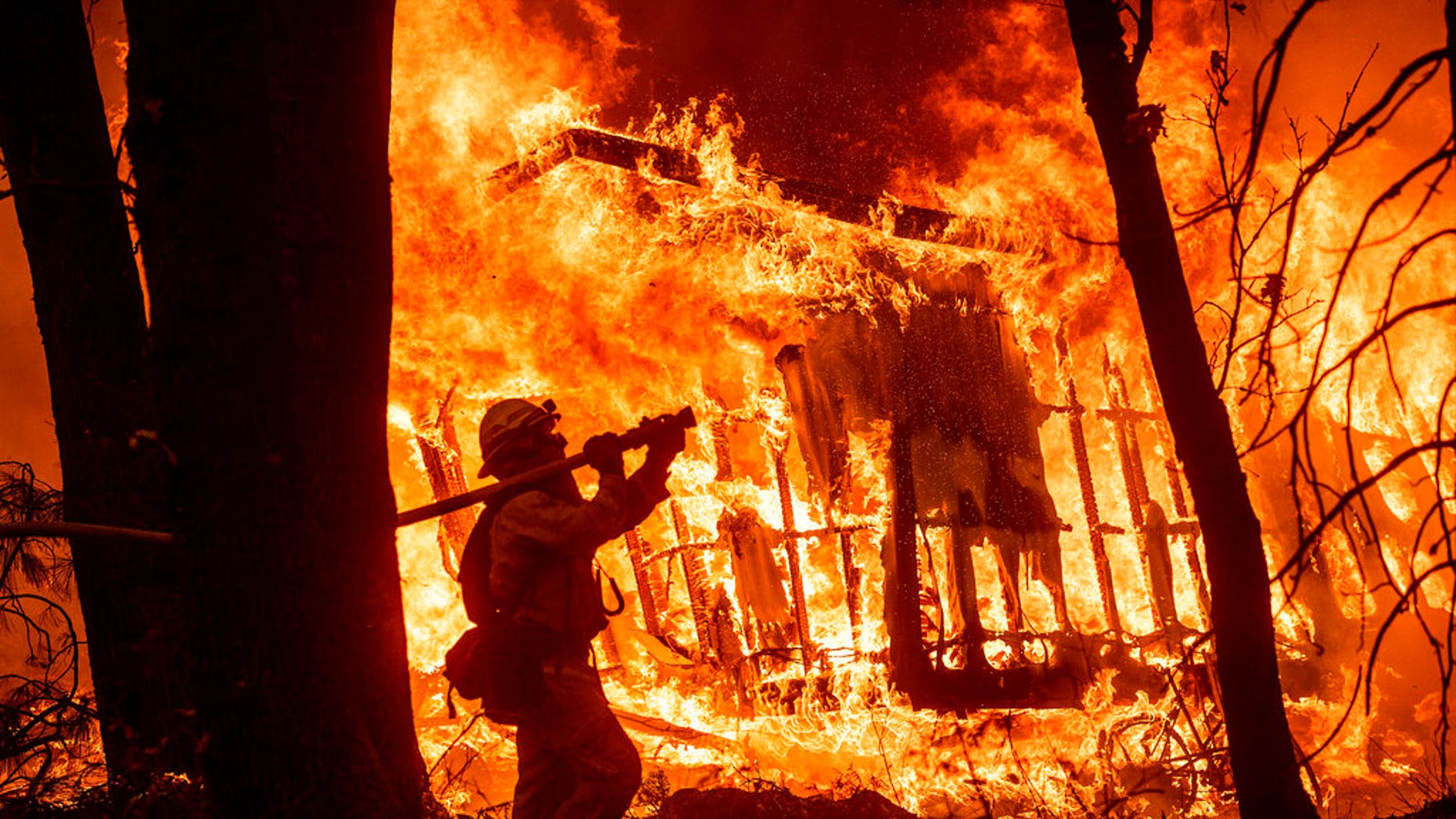 Firefighter Jose Corona sprays water as flames from the Camp Fire consume a home in Magalia, Calif. in November (AP Photo/Noah Berger)