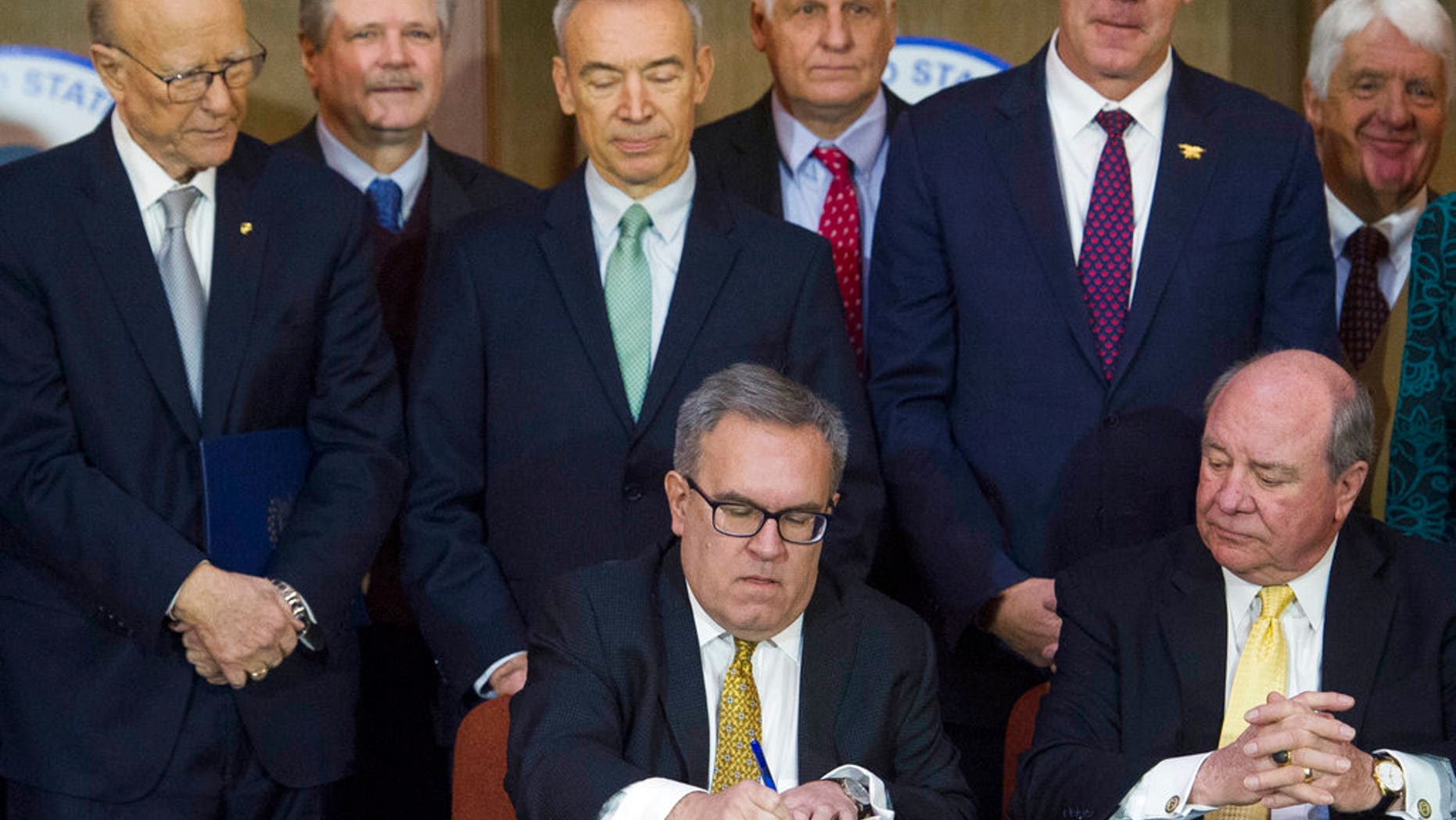 Acting EPA Administrator Andrew Wheeler, seated left, signing an order withdrawing federal protections for countless waterways and wetlands, as Assistant Secretary of the Army for Civil Works Rickey "RD" James, seated right, looks on, at EPA headquarters in Washington on Tuesday. Among those looking on from behind are Senate Agriculture Committee Chairman Pat Ross, R-Kansas, left, and Secretary of the Interior Ryan Zinke, second from right. (AP Photo/Cliff Owen)
