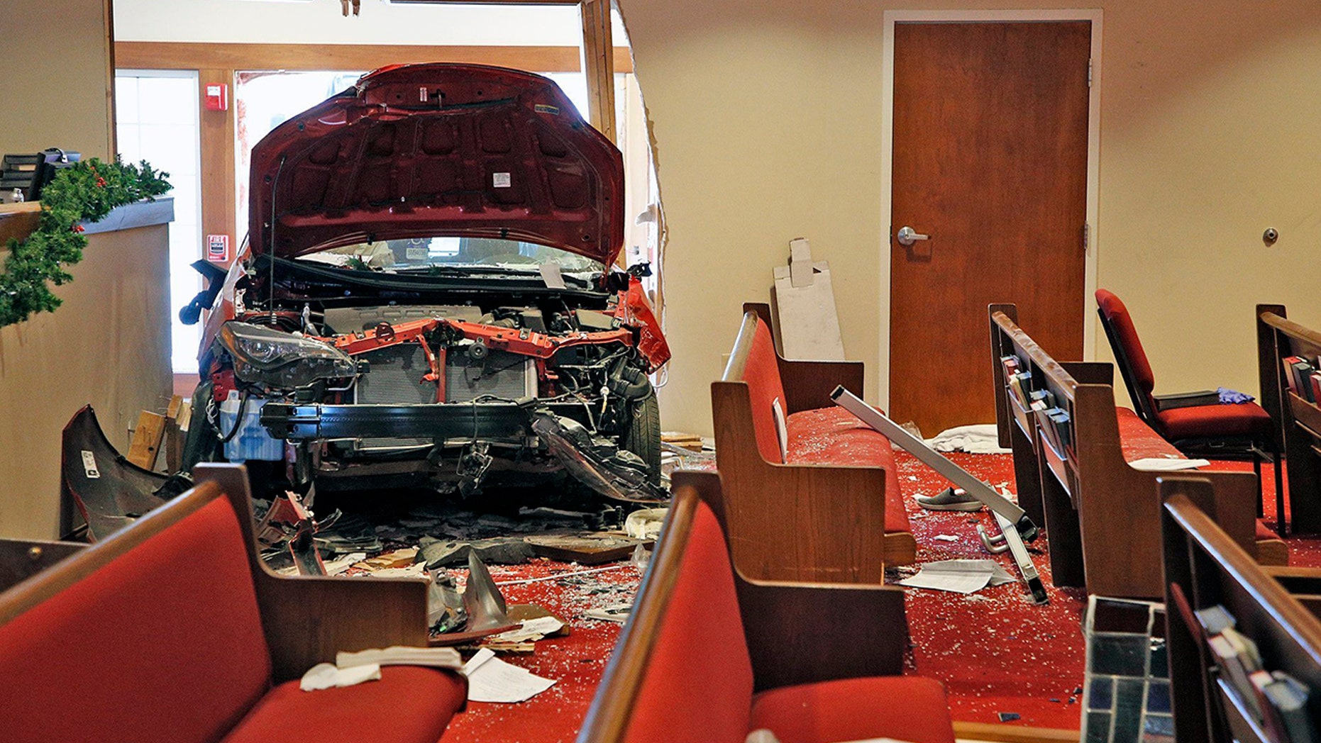 A car that crashed into the entrance of the Crossroads United Methodist Church located at 1100 Hague Avenue is visible from inside of the church on the morning of Sunday, December 23, 2018 in Columbus, Ohio. A woman drove into the church during morning services, injuring several people. (Brooke LaValley/The Columbus Dispatch via AP)