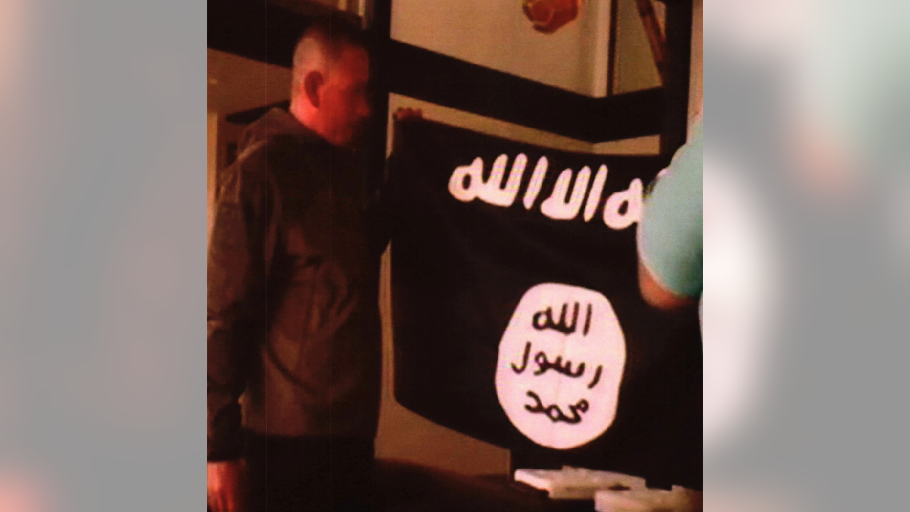 FILE - In this undated file image taken from FBI video and provided by the U.S. Attorney's Office in Hawaii on Thursday, July 13, 2017, Army Sgt. 1st Class Ikaika Kang holds an Islamic State group flag after allegedly pledging allegiance to the group at a house in Honolulu. On Tuesday, Dec. 4, 2018, Kang is scheduled to be sentenced for trying to help the Islamic State group. (FBI/U.S Attorney's Office, District of Hawaii via AP, File)